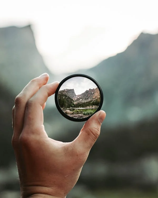 Lens focusing on a mountain landscape, representing discovery