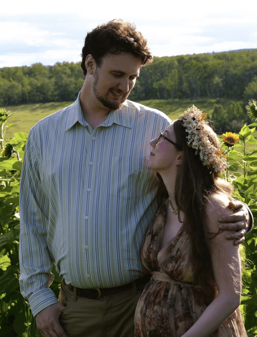 A couple stands outdoors at sunset.