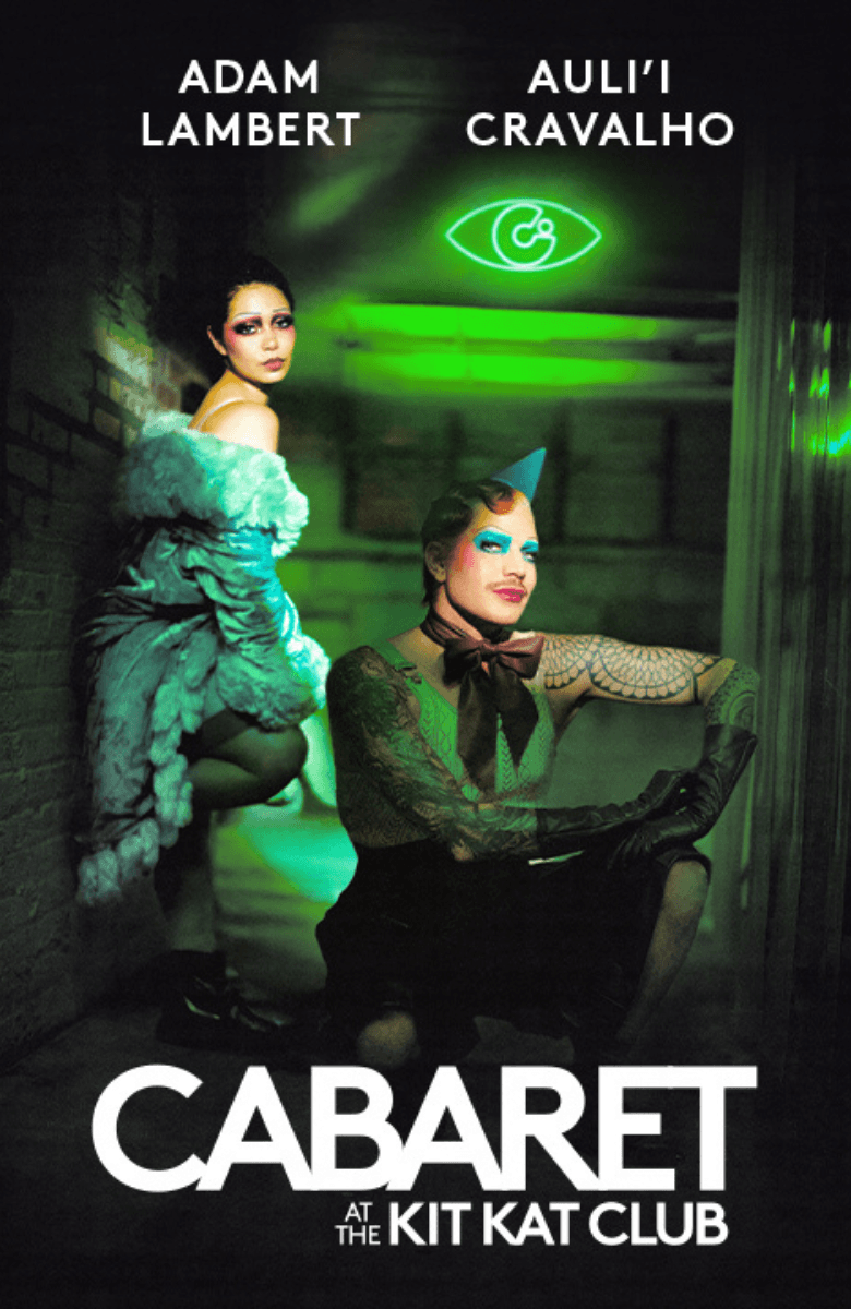 Cabaret at the Kit Kat Club on Broadway. In a green lit alley with the Kit Kat Club logo in a neon light in the top right.  Auli'i Cravalho (as Sally Bowles) leans against the wall, one foot against the wall. Adam Lambert (as the Emcee) squats in the center of the alley in a puddle. He is topless, wearing a tie and a birthday hat.