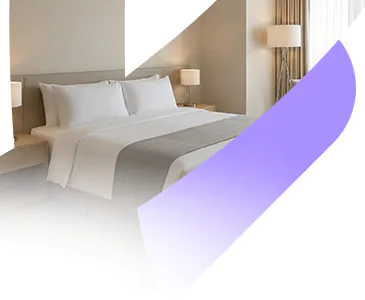 Quarto de hotel confortável com cama de casal bem arrumada e iluminação acolhedora, representando as hospedagens selecionadas pela Livare Viagens no Circuito Andino.