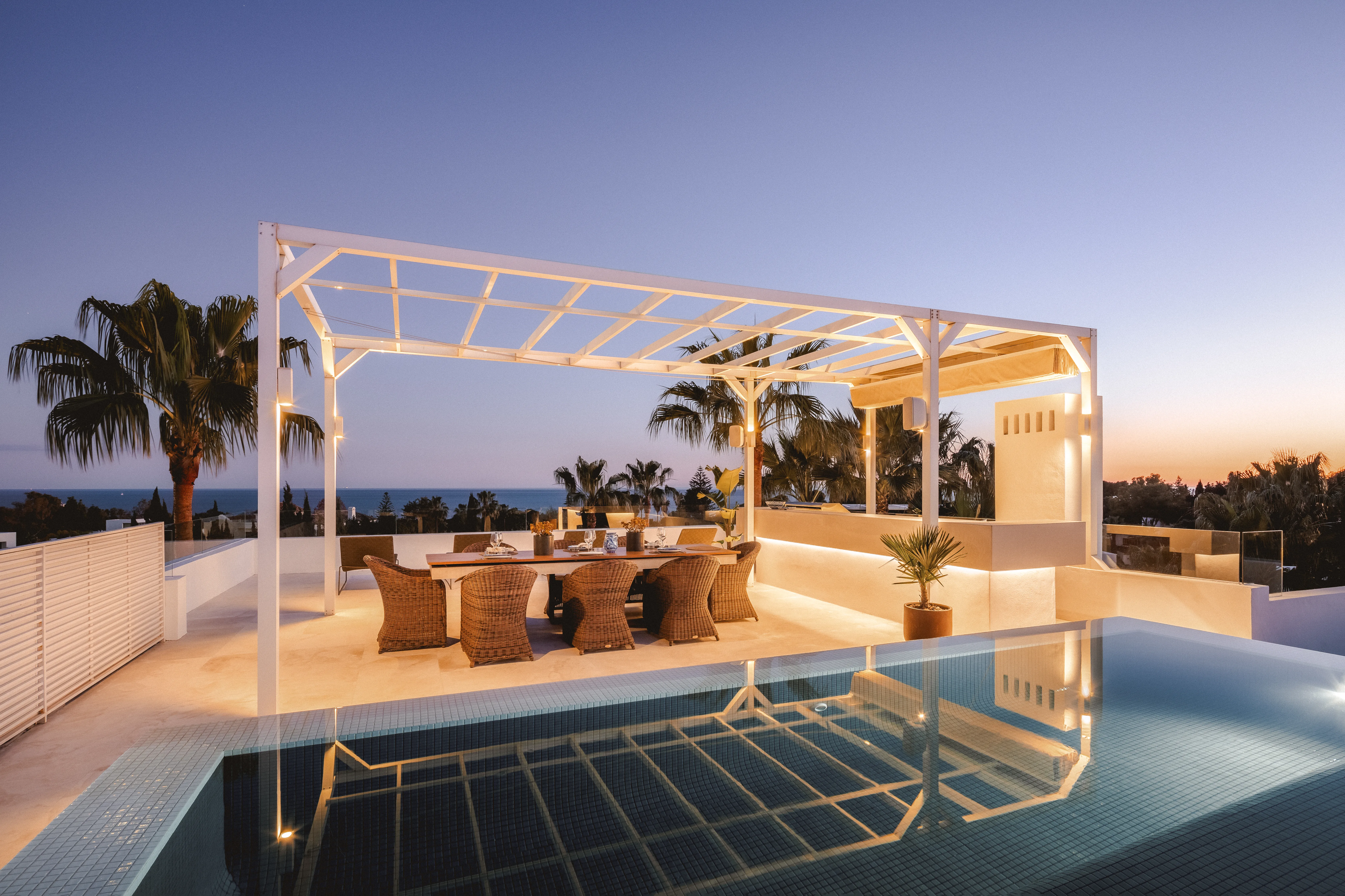 Outdoor dining area with bespoke pergola, poolside lounge and Mediterranean surroundings.