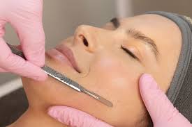 A woman lying down with a towel wrapped around her head, her face glowing with facial oil. She has a peaceful expression, enjoying a skincare treatment.