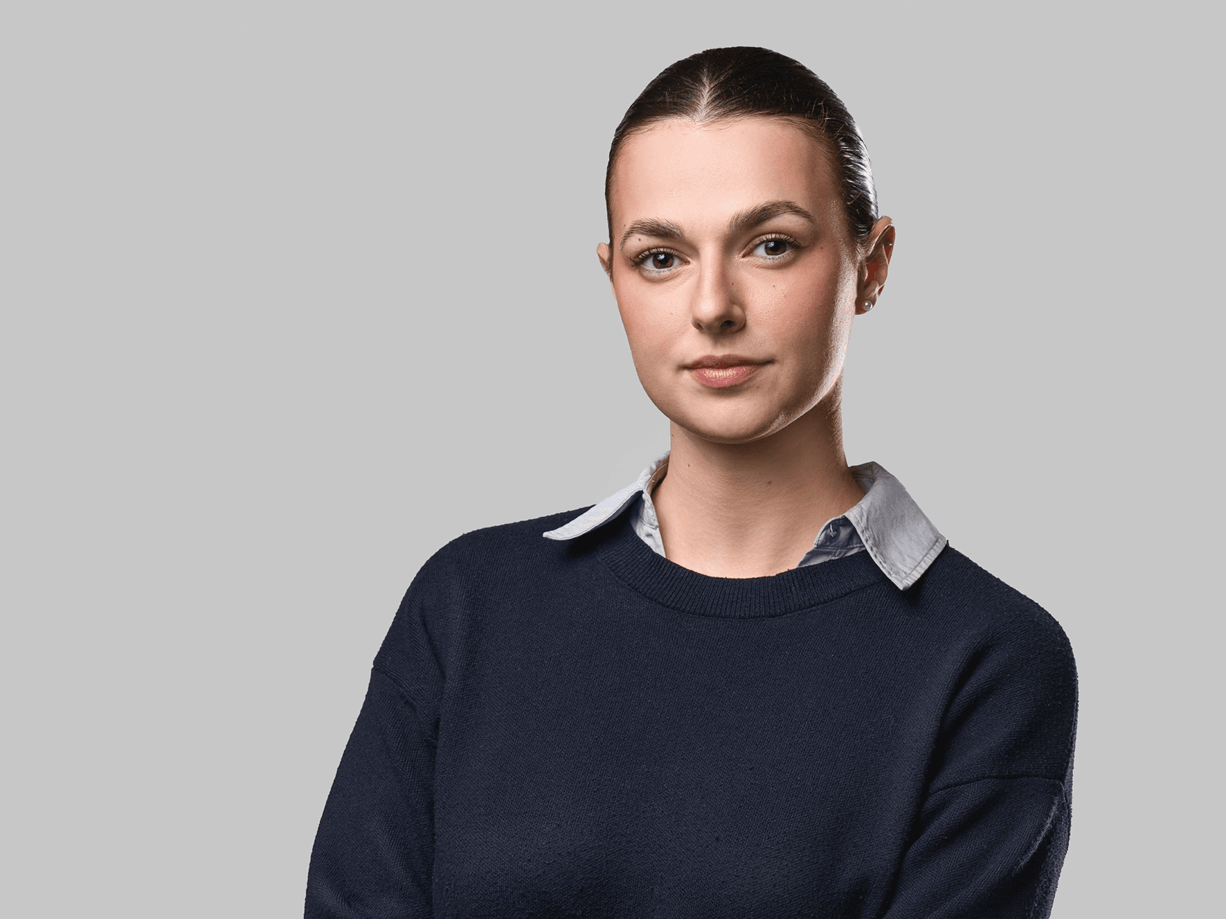 Poslovni portret žene sa prekrštenim rukama na neutralnoj sivoj pozadini