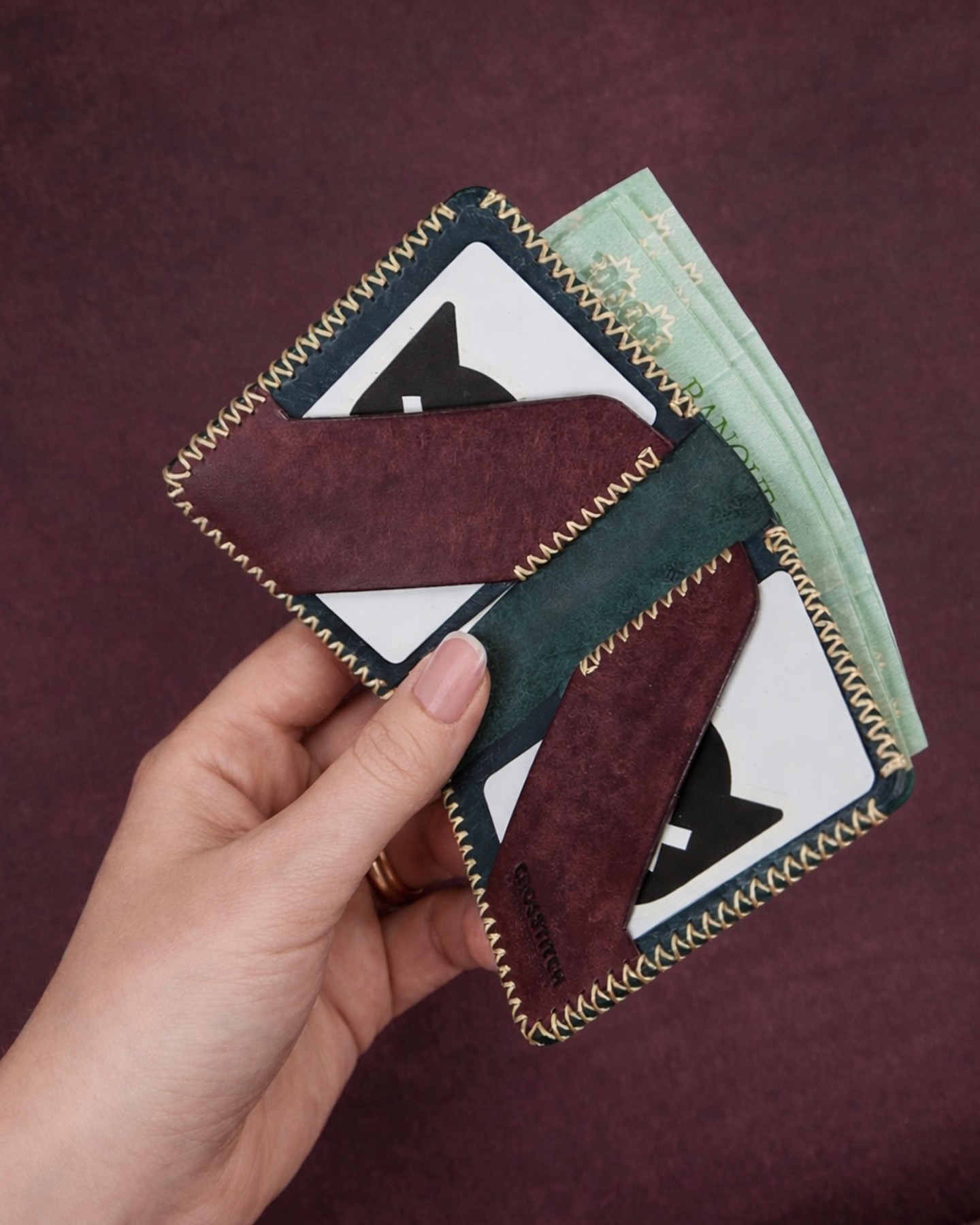 Crosstitch Leather bifold wallet in brown and green leather featuring yellow stitching, card slots, and cash compartment.