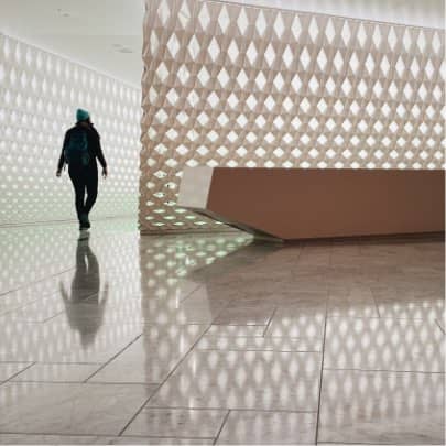 Smiling young man with short hair poses against a dark background, wearing a green button-up shirt.