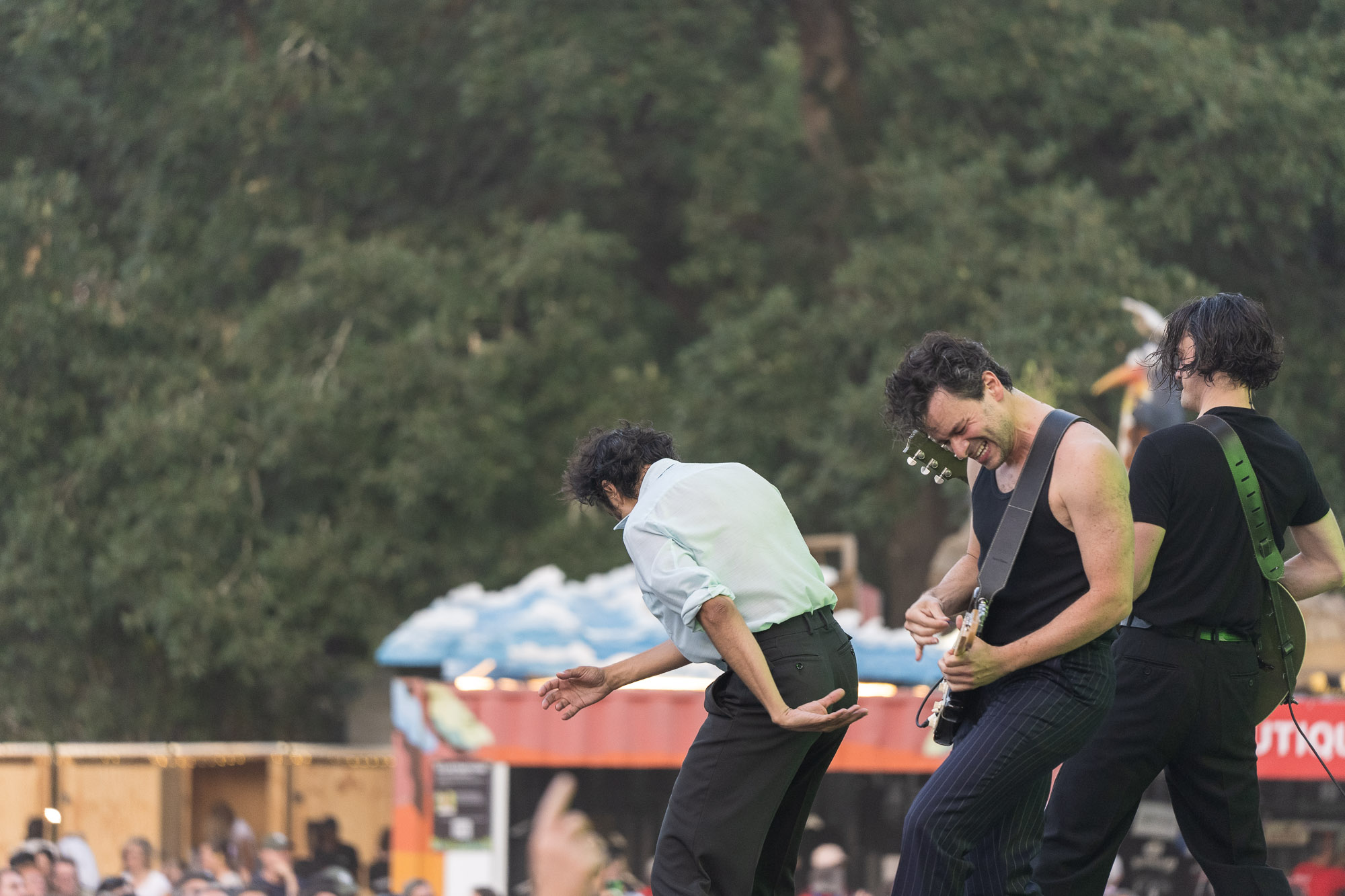 Deux musiciens penchés en avant avec une guitare électrique, dans l’ambiance du festival en plein air.