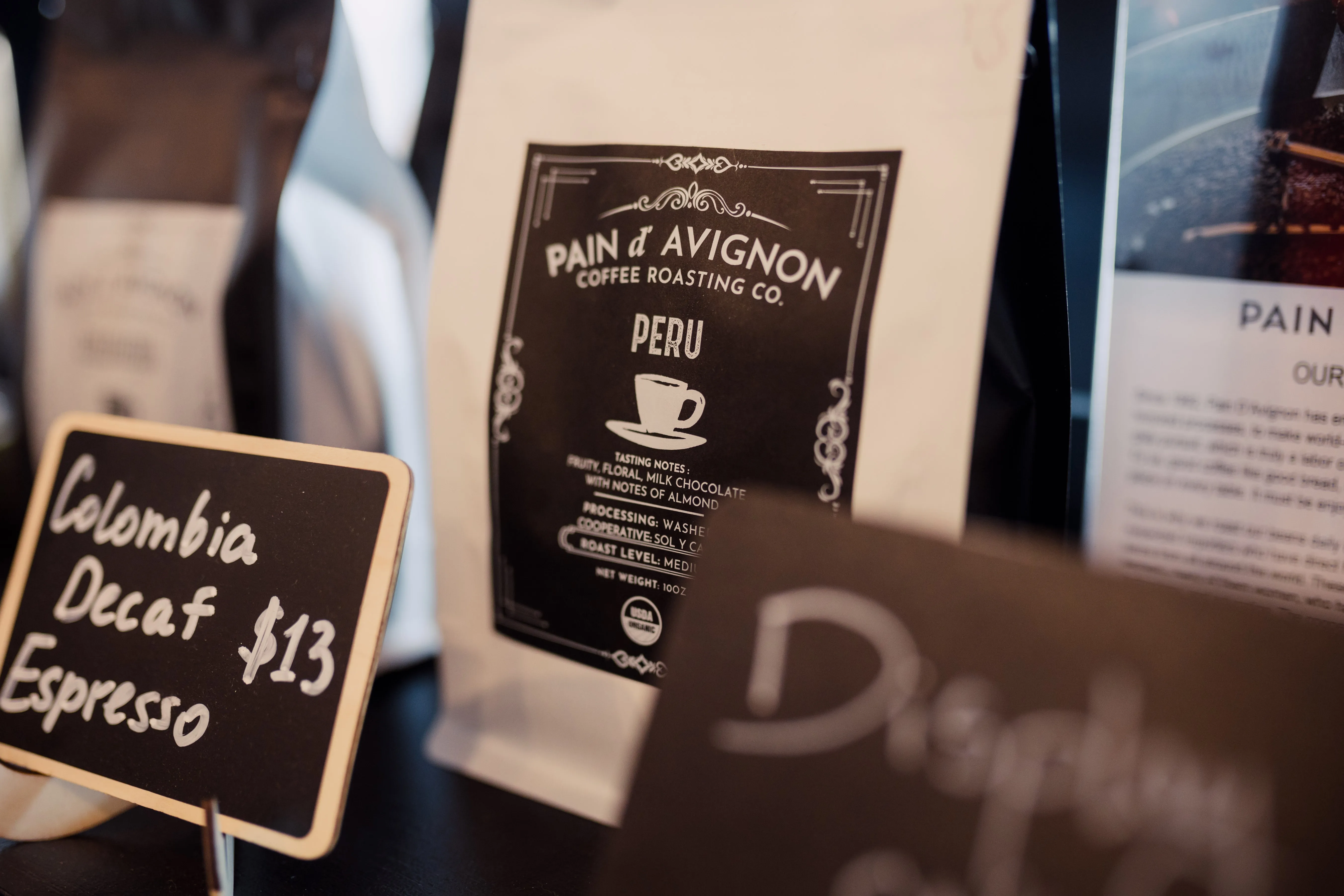 Pain d'Avignon Coffee Roasting Co. retail display — Peru single-origin coffee bag with chalkboard pricing and branded signage