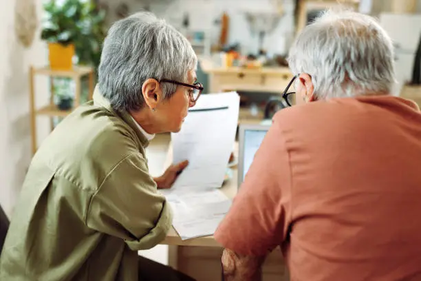 Retired couple reviewing financial documents at the kitchen table