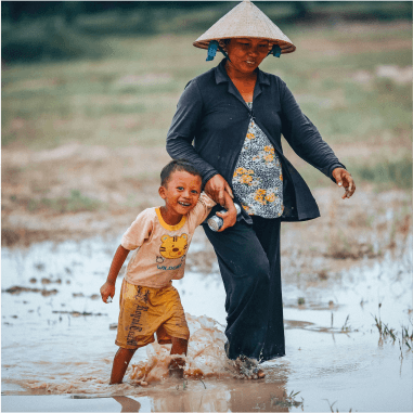 A woman and child walking hand in hand through a rice field