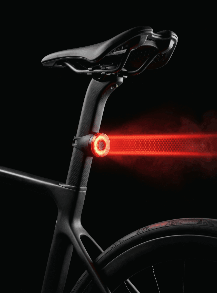 Close-up of a bicycle with a red rear light against a dark background