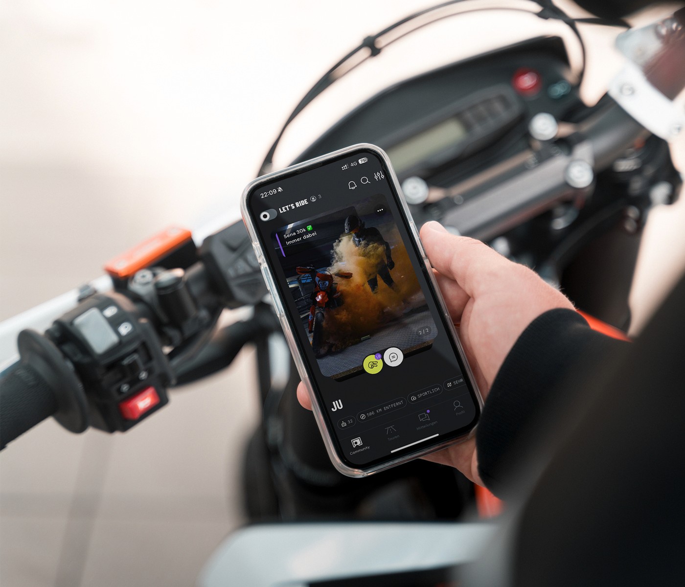 Ein Motorradfahrer schaut auf sein Smartphone, auf dem die Yomoko-App angezeigt wird.