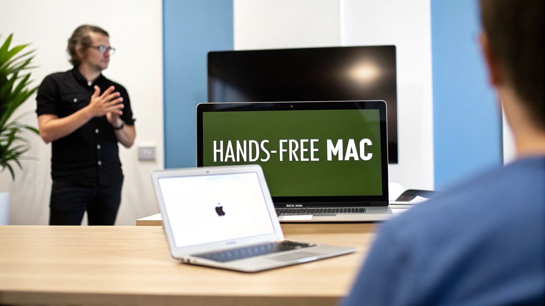 A presenter demonstrates 'Hands-Free Mac' on a laptop during a tech presentation to an audience.