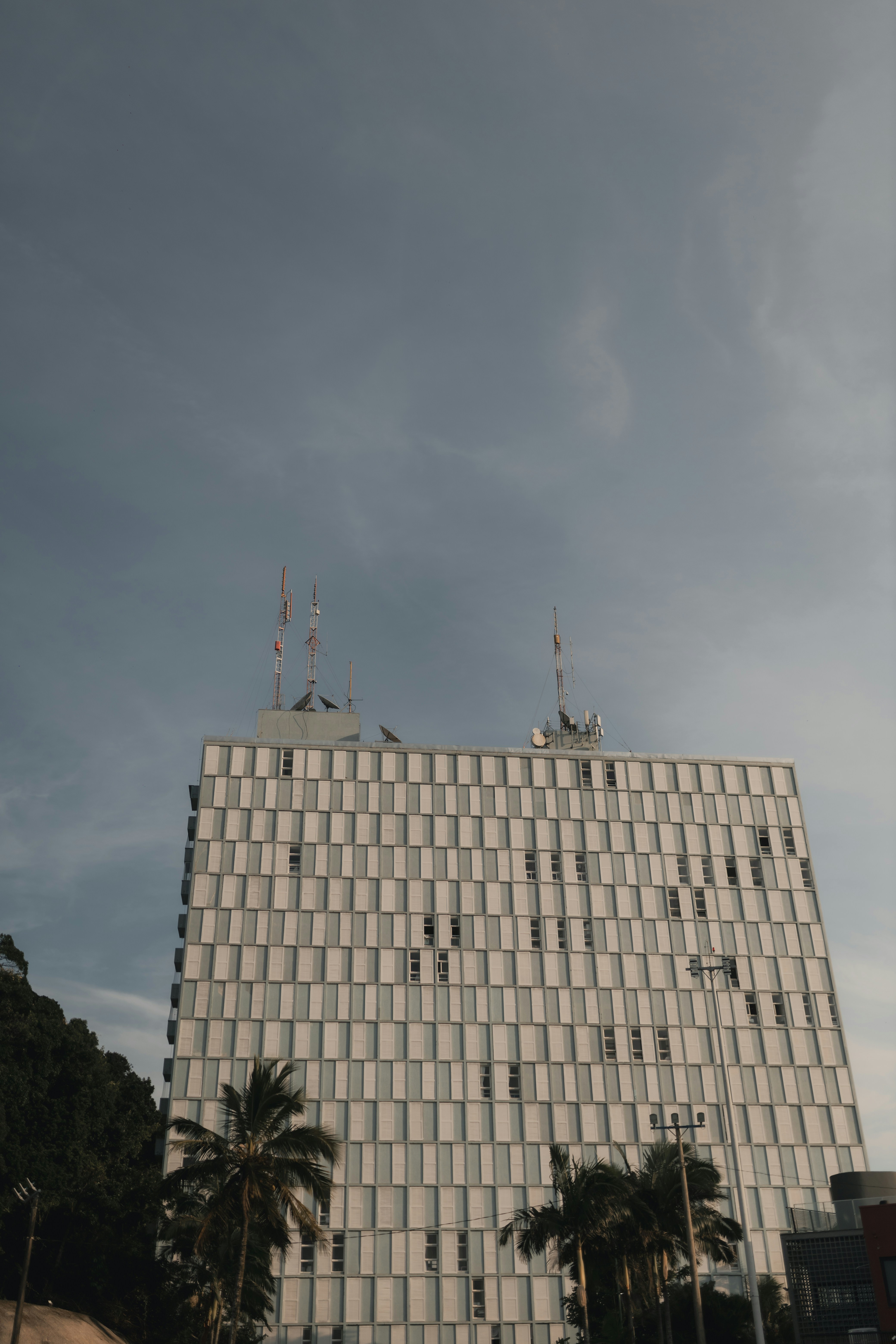 A modern building with antennas under cloudy skies.