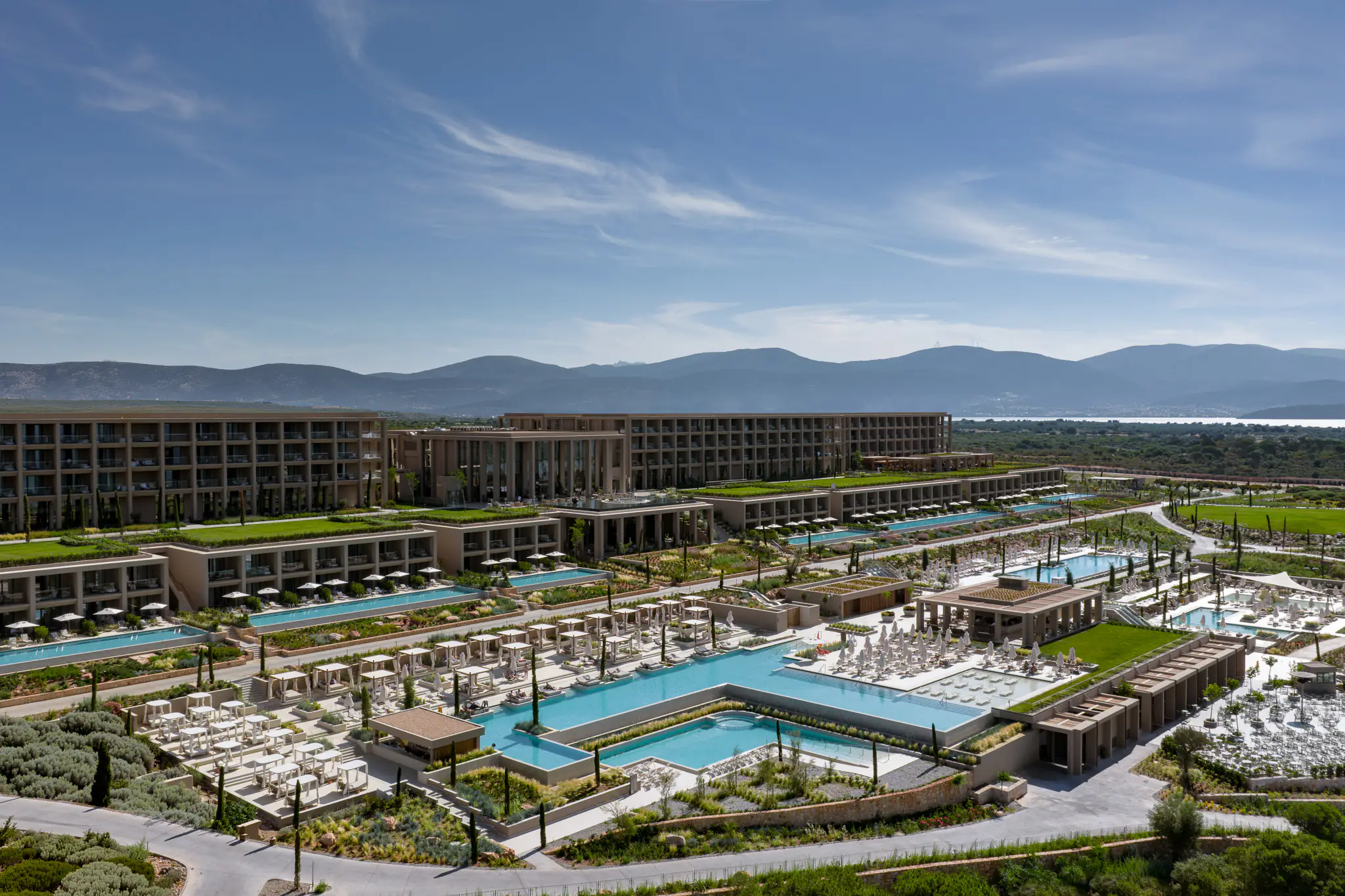 Aerial view of the resort with pools, gardens and mountains behind