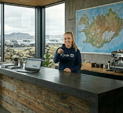 Woman holding keys standing behind a reception counter with a map on the wall.