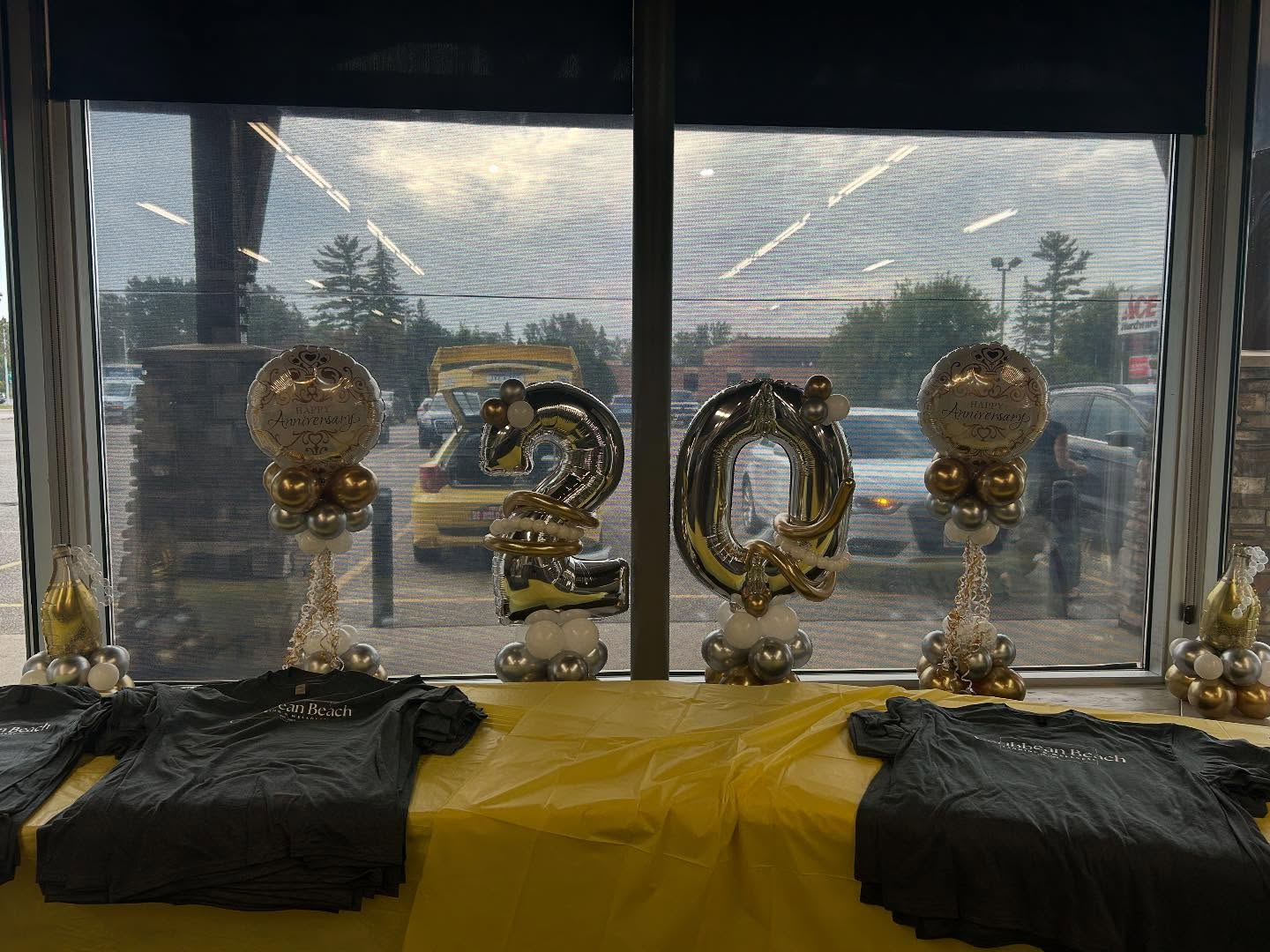 Elegant gold and white balloon decorations arranged around windows with golden centerpieces for a formal event by Be Bold Balloons