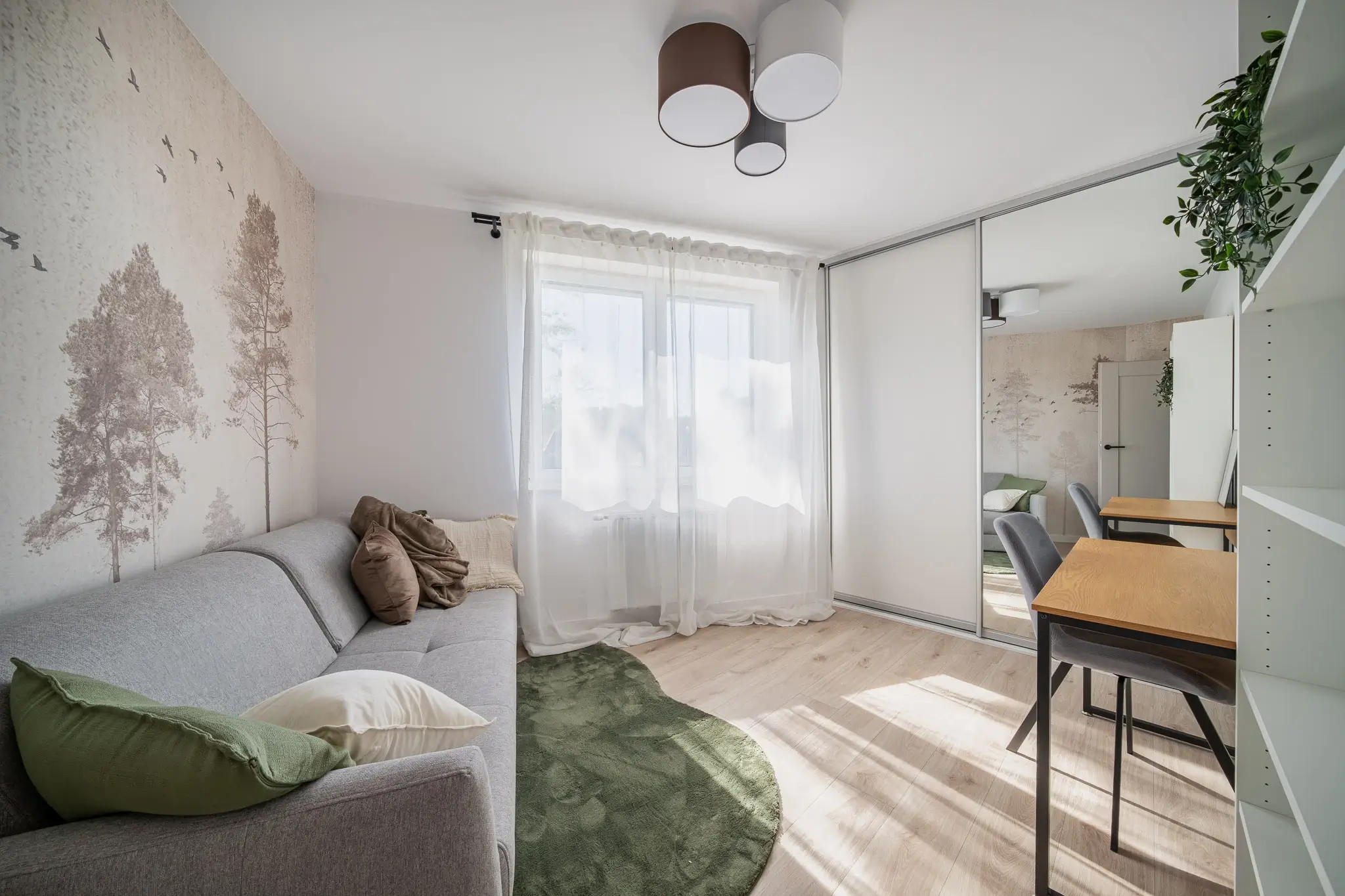 Przytulny pokój z kanapą i dużą szafą wnękową z lustrzanymi drzwiami przesuwnymi.