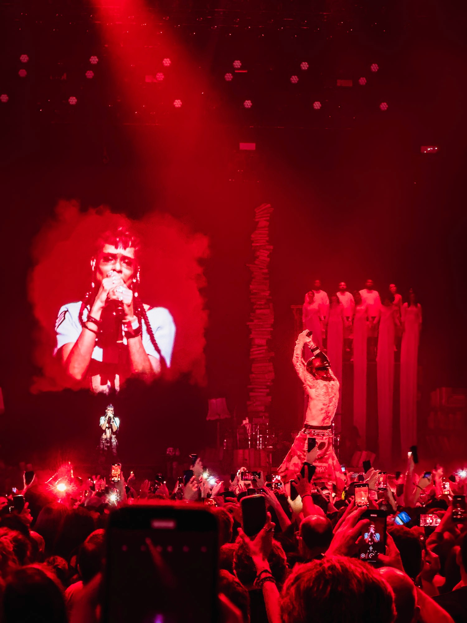 Chanteur en gros plan sur écran géant rouge, scénographie en éventail de lumière