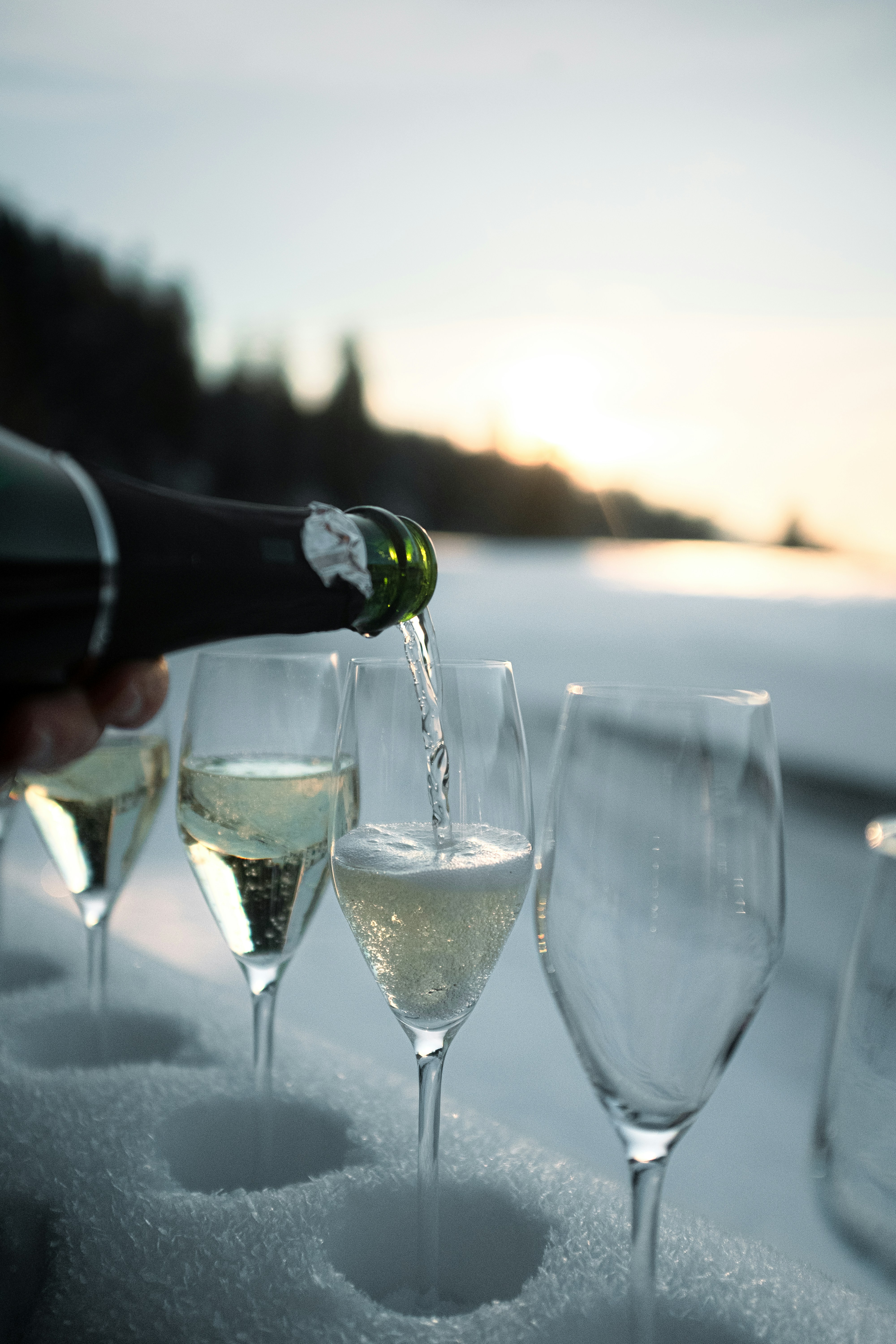 Champagne being poured into glasses in the snow.