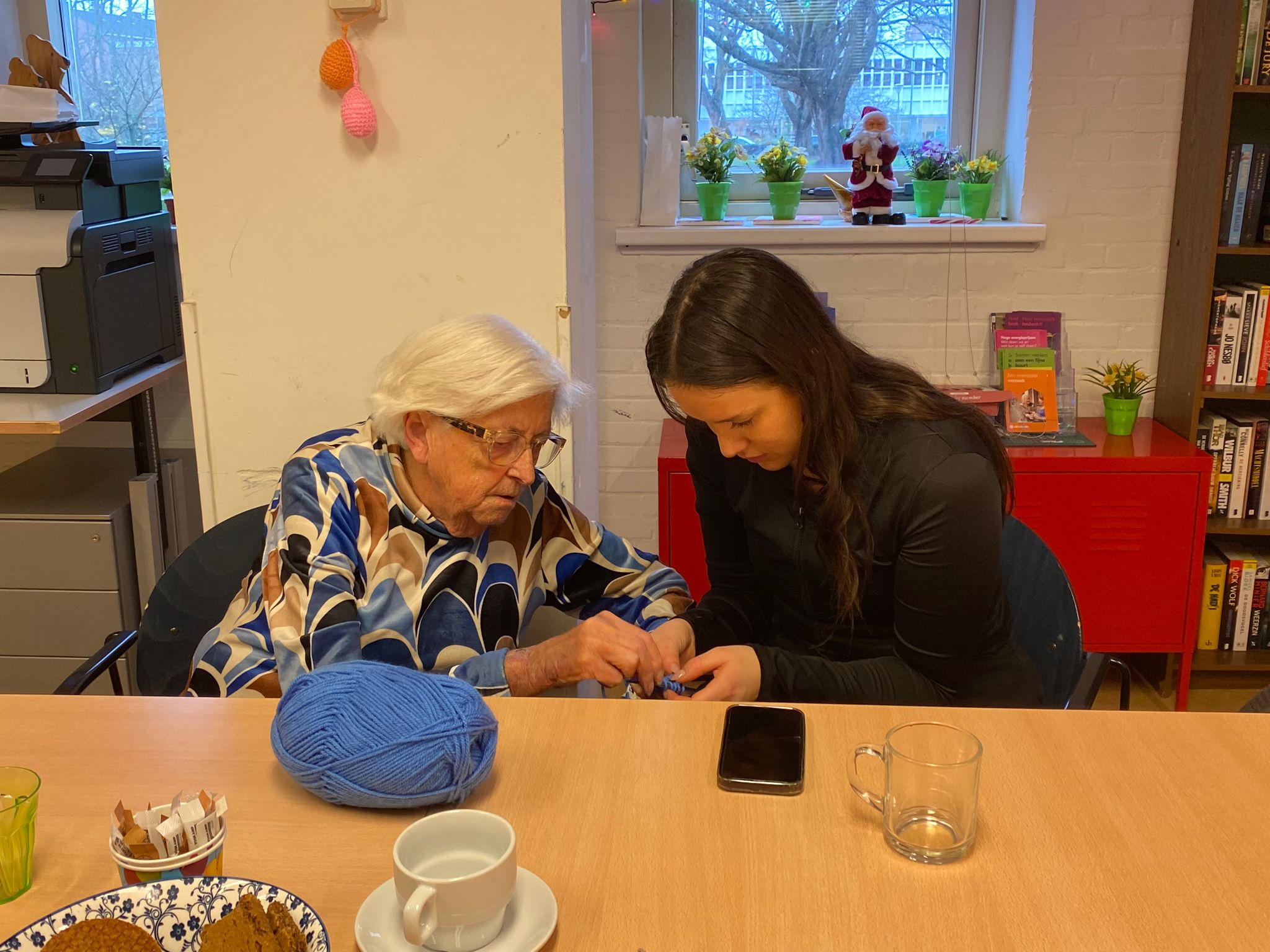 Student helpt een oudere buurtbewoner met haar telefoon