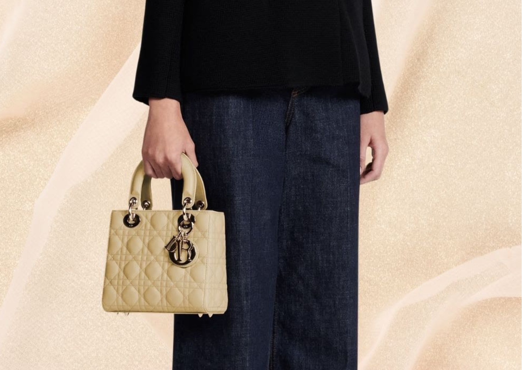 A stylish lady holding a beige/yellow Lady Dior bag, that is chic. The bag exudes elegance, as the eoman wearing fashionable wide-leg jeans hold it gracefully.