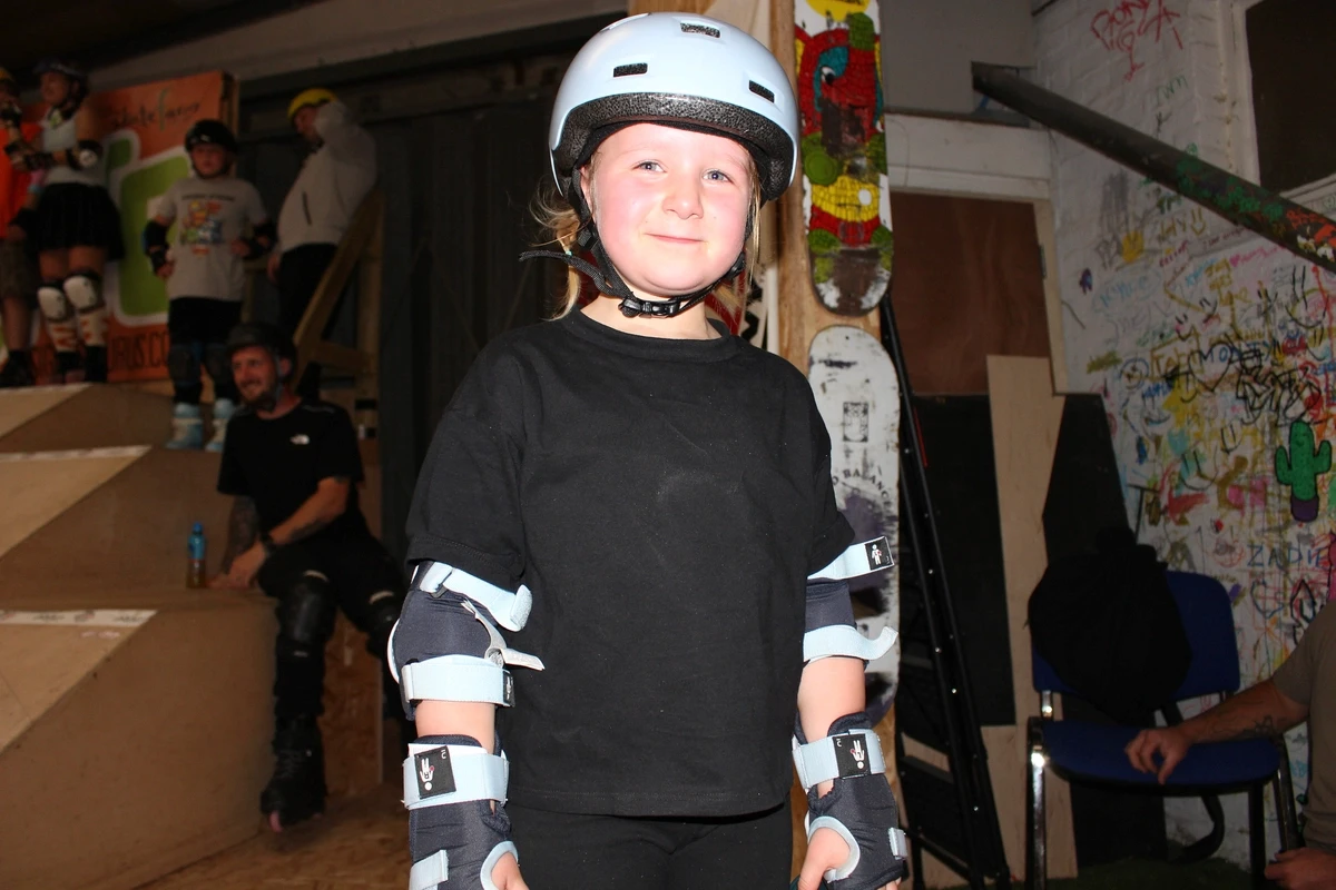 A young skater wearing a helmet and protective gear at The Skate Farm indoor skatepark in Sussex