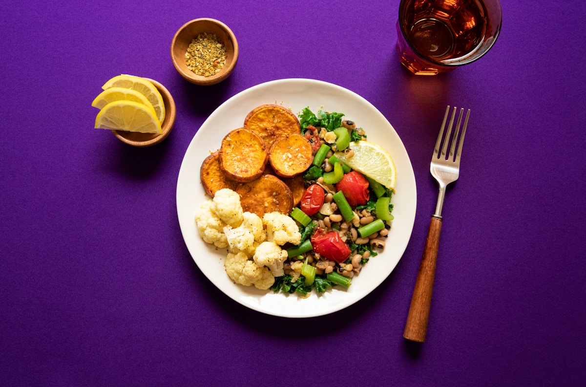 A small, neatly portioned plate with sweet potato, cauliflower and a fresh bean salad, showing how meals feel satisfying at smaller portions on a GLP-1 medication