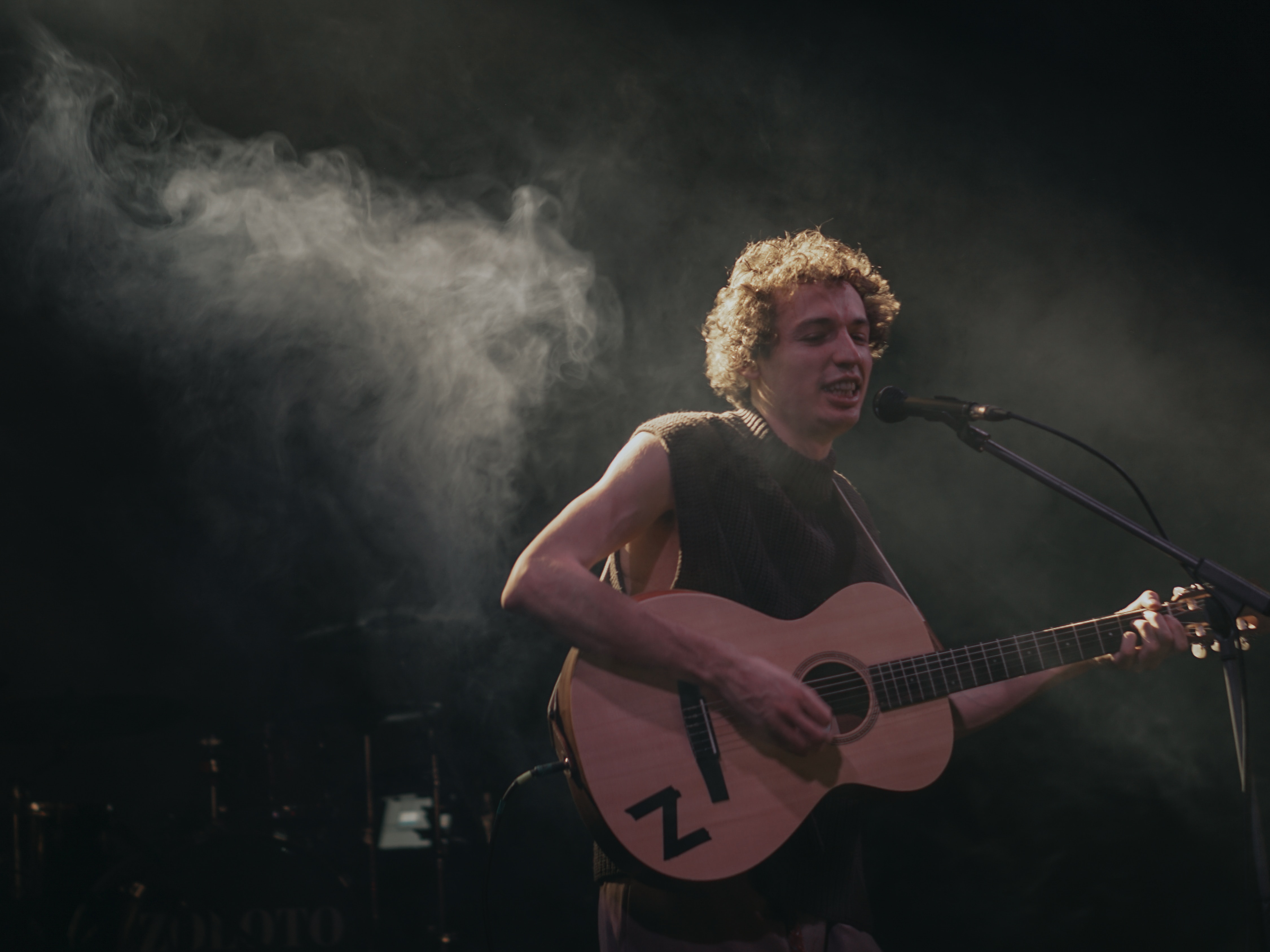 man on stage with guitar with some smoke in background - how to do ai voices