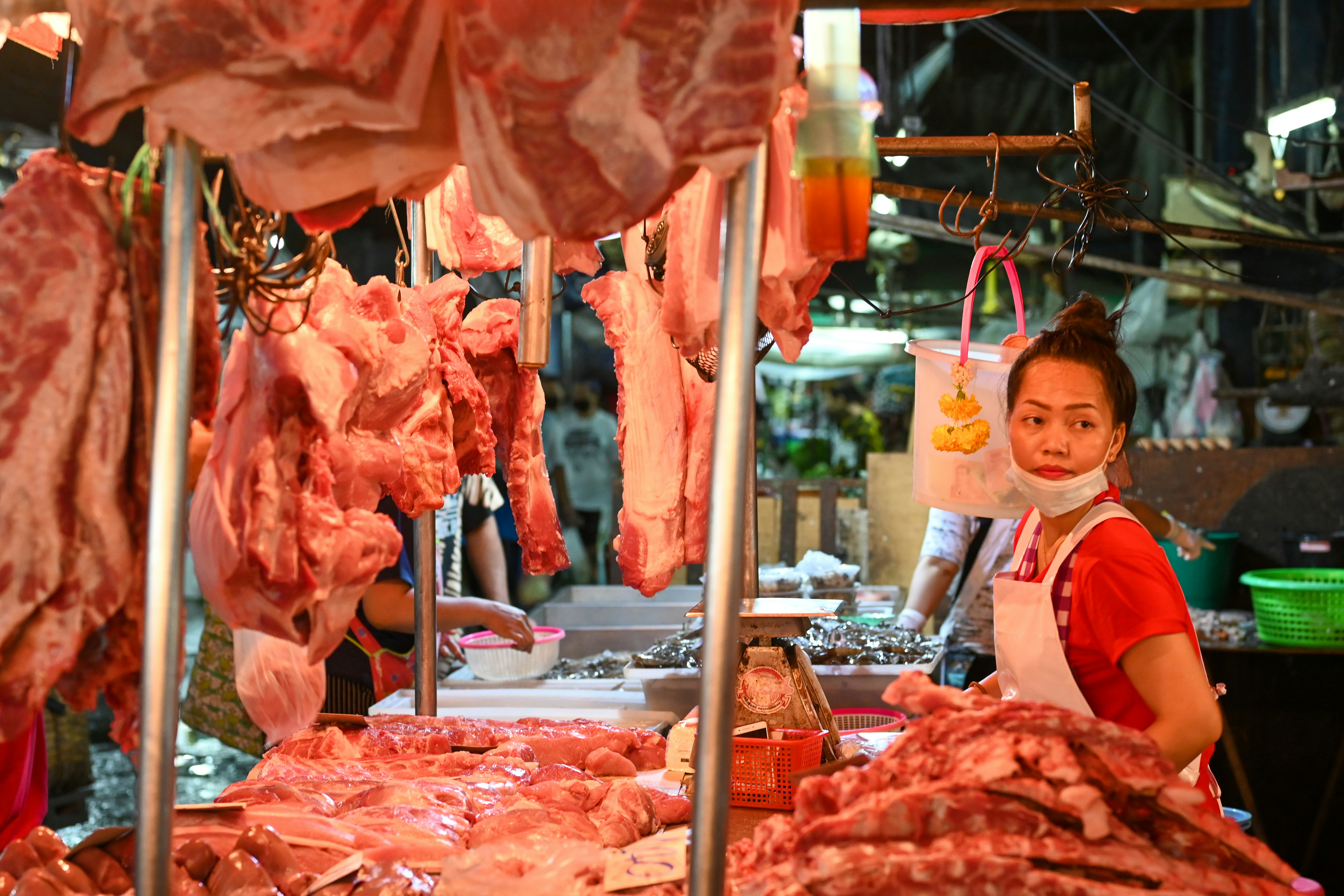 woman in white crew neck t-shirt standing near raw meat