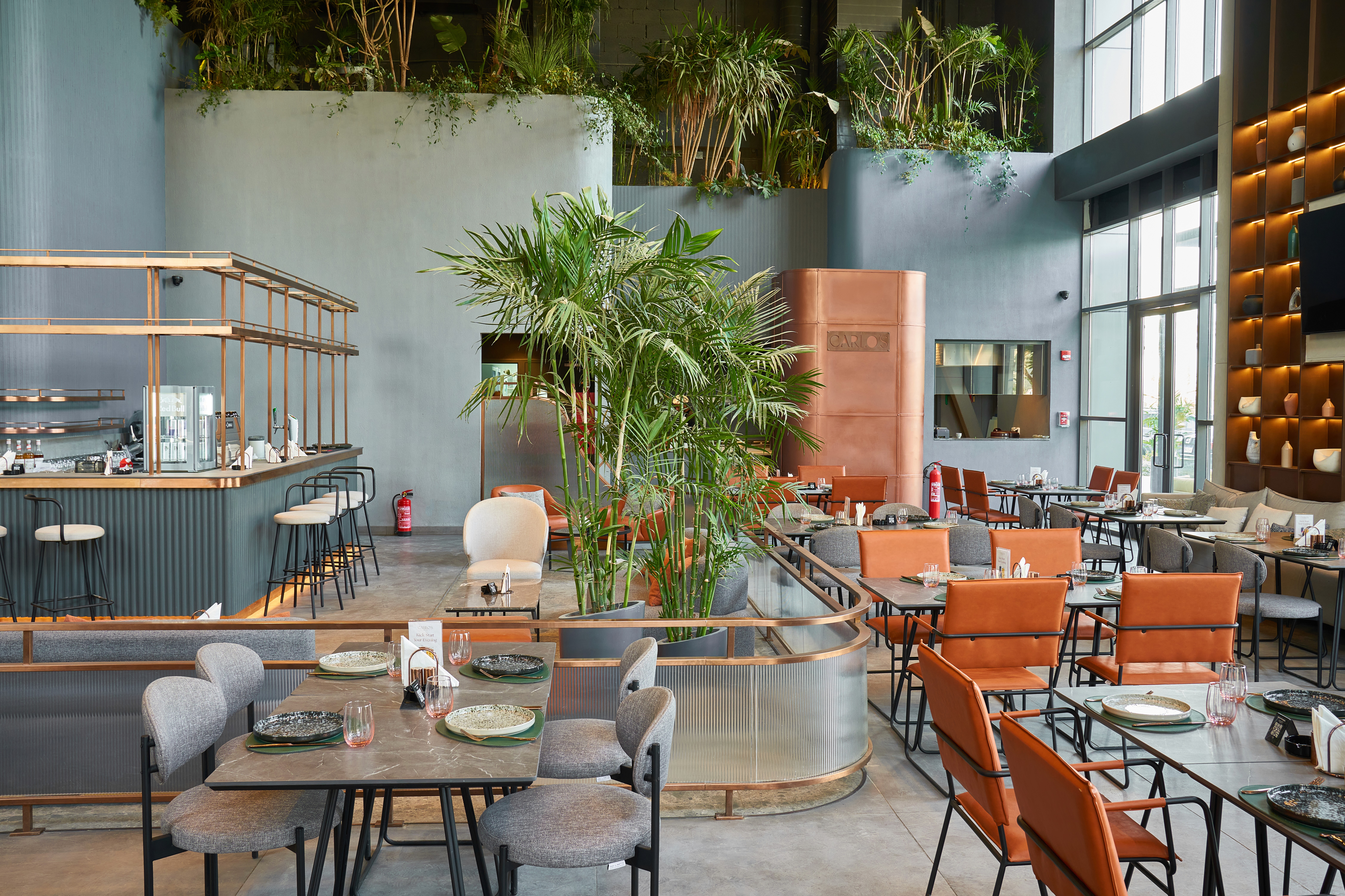 An overhead shot of a large oval plate featuring sliced, roasted duck, half glazed with a sauce, served over two thin pancakes and alongside steamed bok choy, surrounded by small bowls of condiments like scallions, sauce, salt, and carrot shreds.