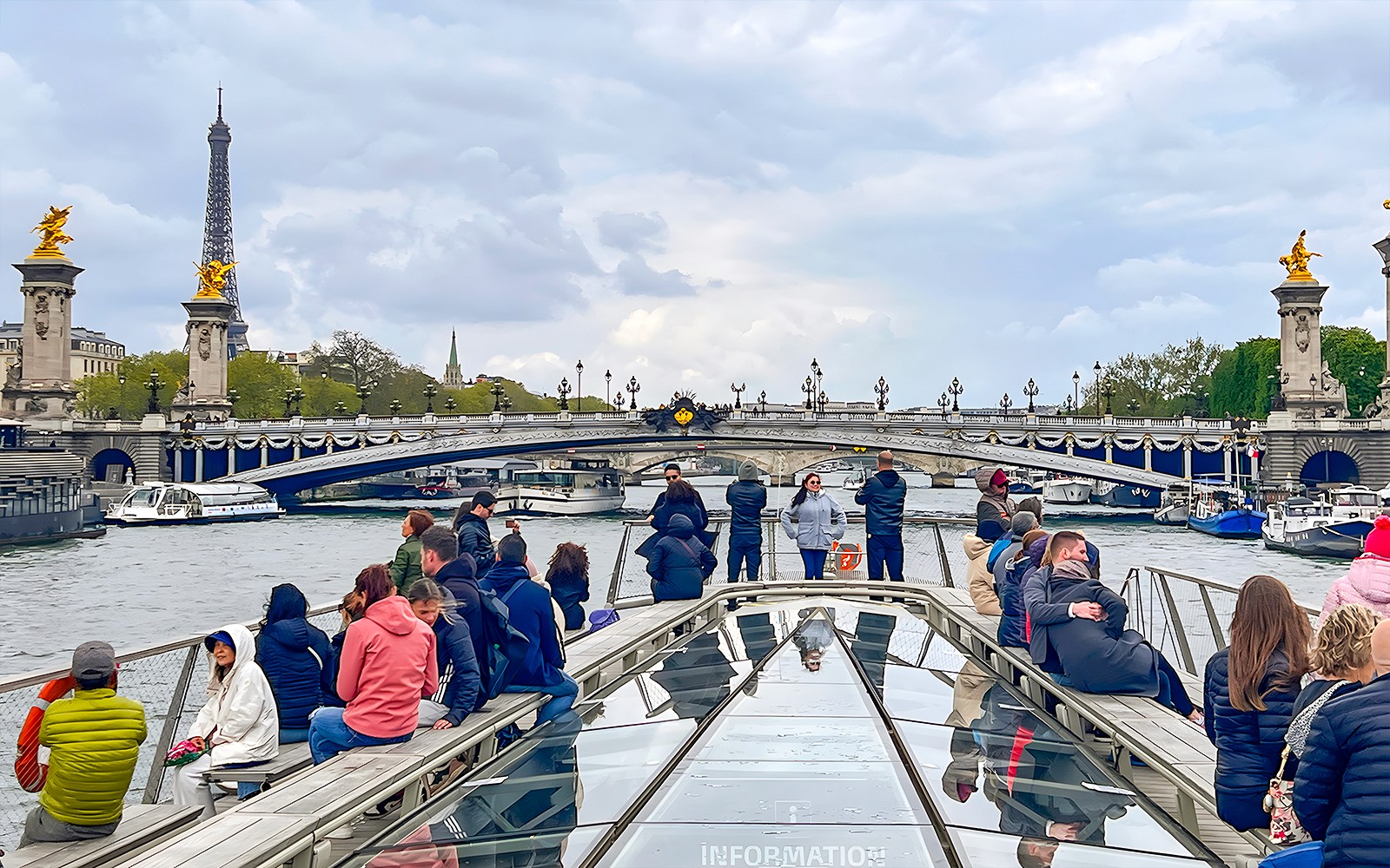 Tourists on a Seine River cruise with Eiffel Tower and Pont Alexandre III in view, Paris.