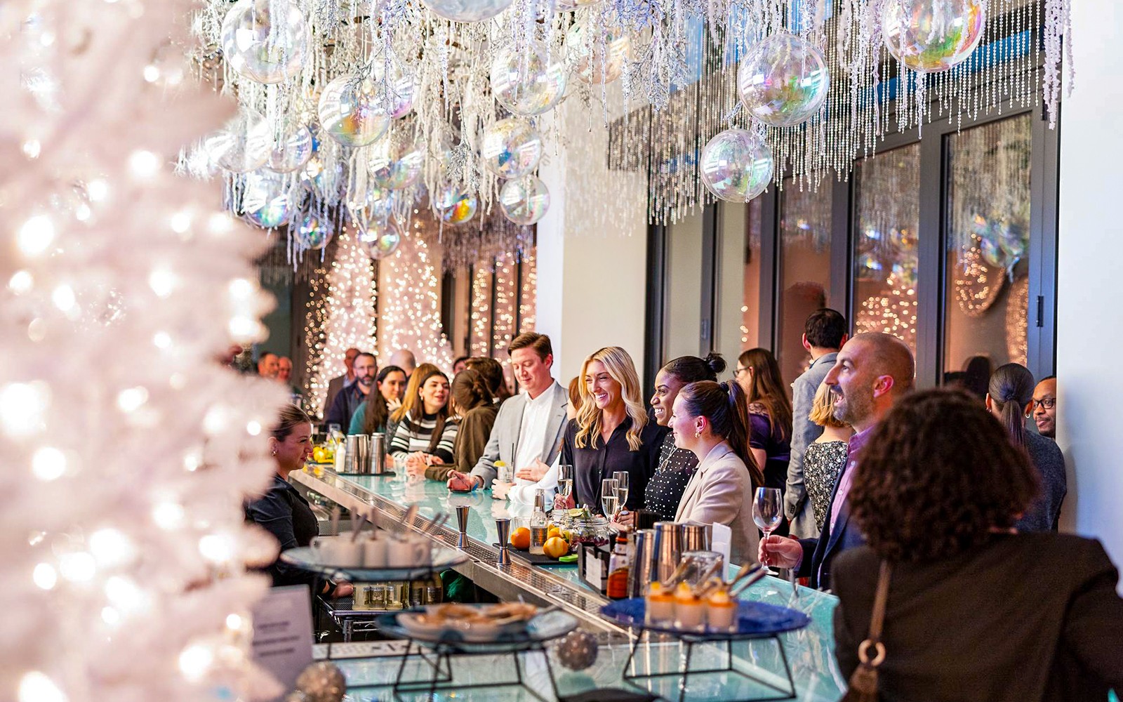 Guests enjoying drinks at the winter-themed bar in View Boston, with festive decorations and lights.
