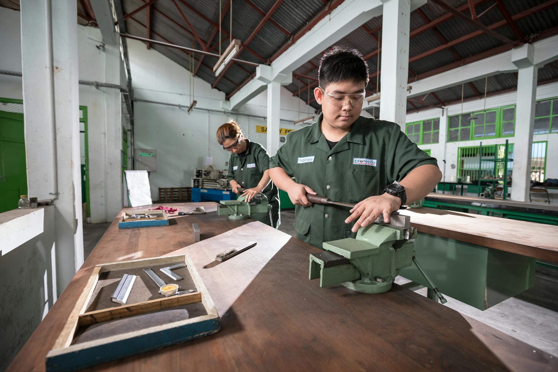 A student in a vocational workshop wearing safety goggles while operating a woodworking lathe for a technical program.