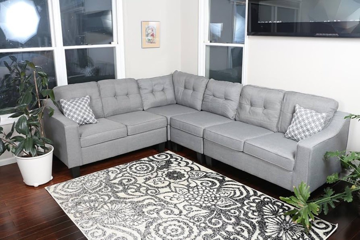 Gray Oliver Smith s295 sectional sofa in a cozy corner of a living room with a patterned rug and indoor plants