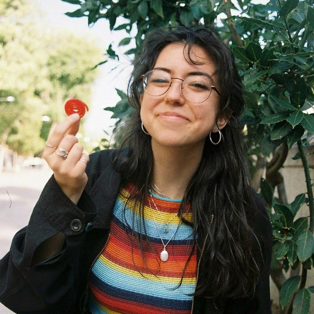 A thoughtful young person with dark hair gazes to the side, captured in soft black and white lighting.