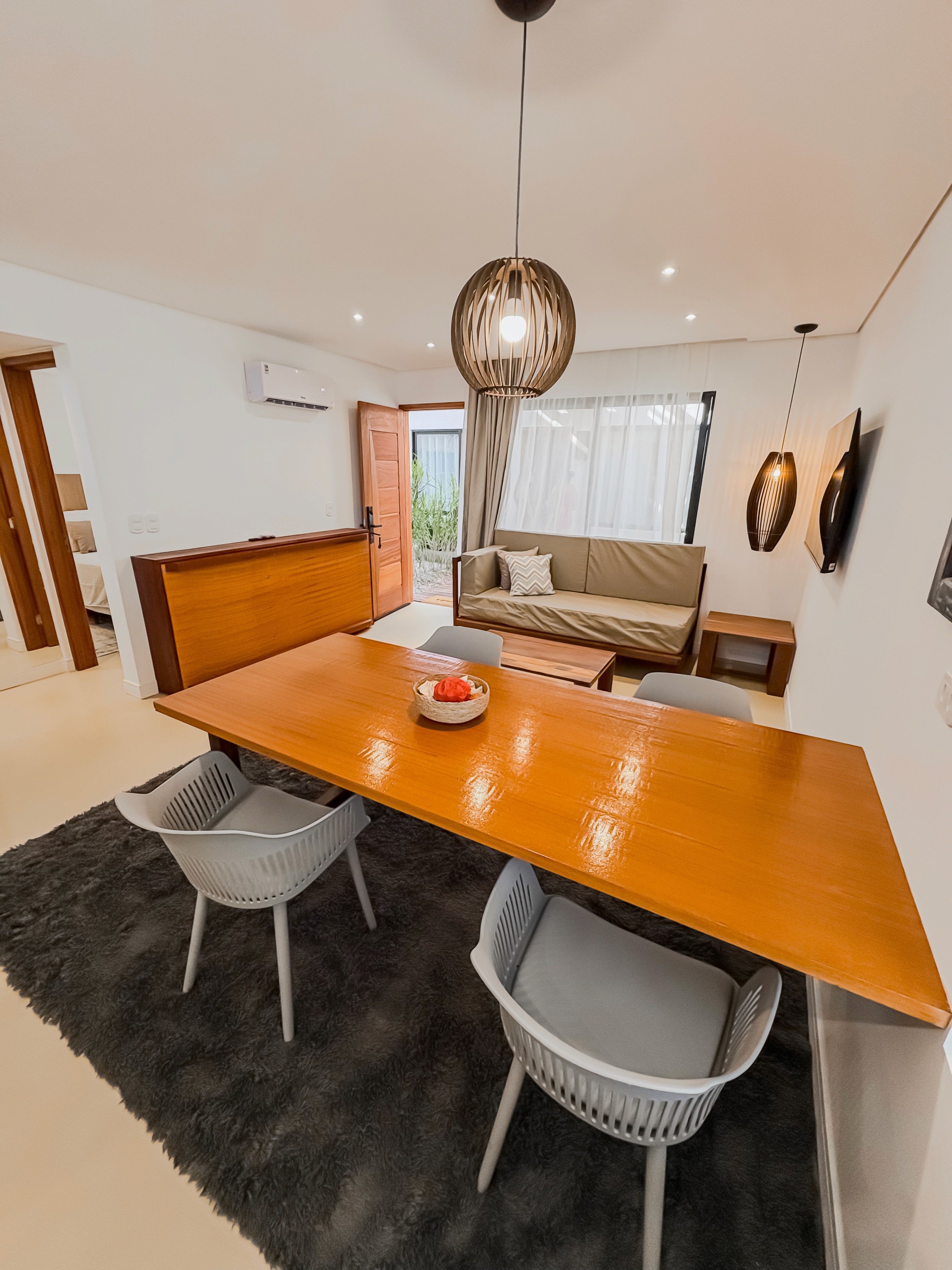 View from patio into the suite, surrounded by lush greenery, queen bed framed inside with neutral-toned decor.