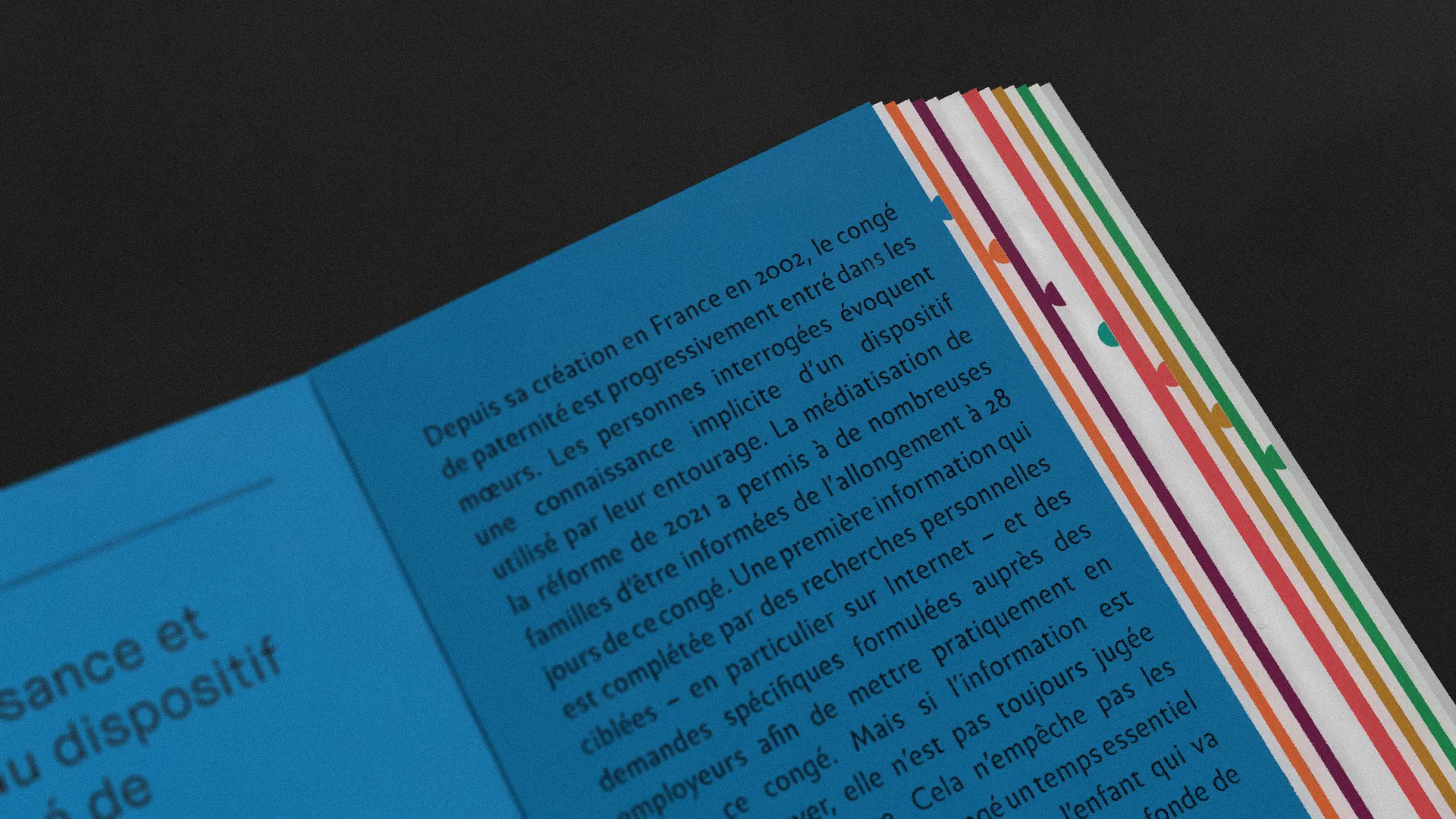 Gros plan sur une page intérieure bleue d'une brochure traitant de la réforme du congé paternité en France. Sur la tranche droite, un système d'onglets colorés (rouge, orange, vert, violet) permet de naviguer dans les différentes sections du rapport.