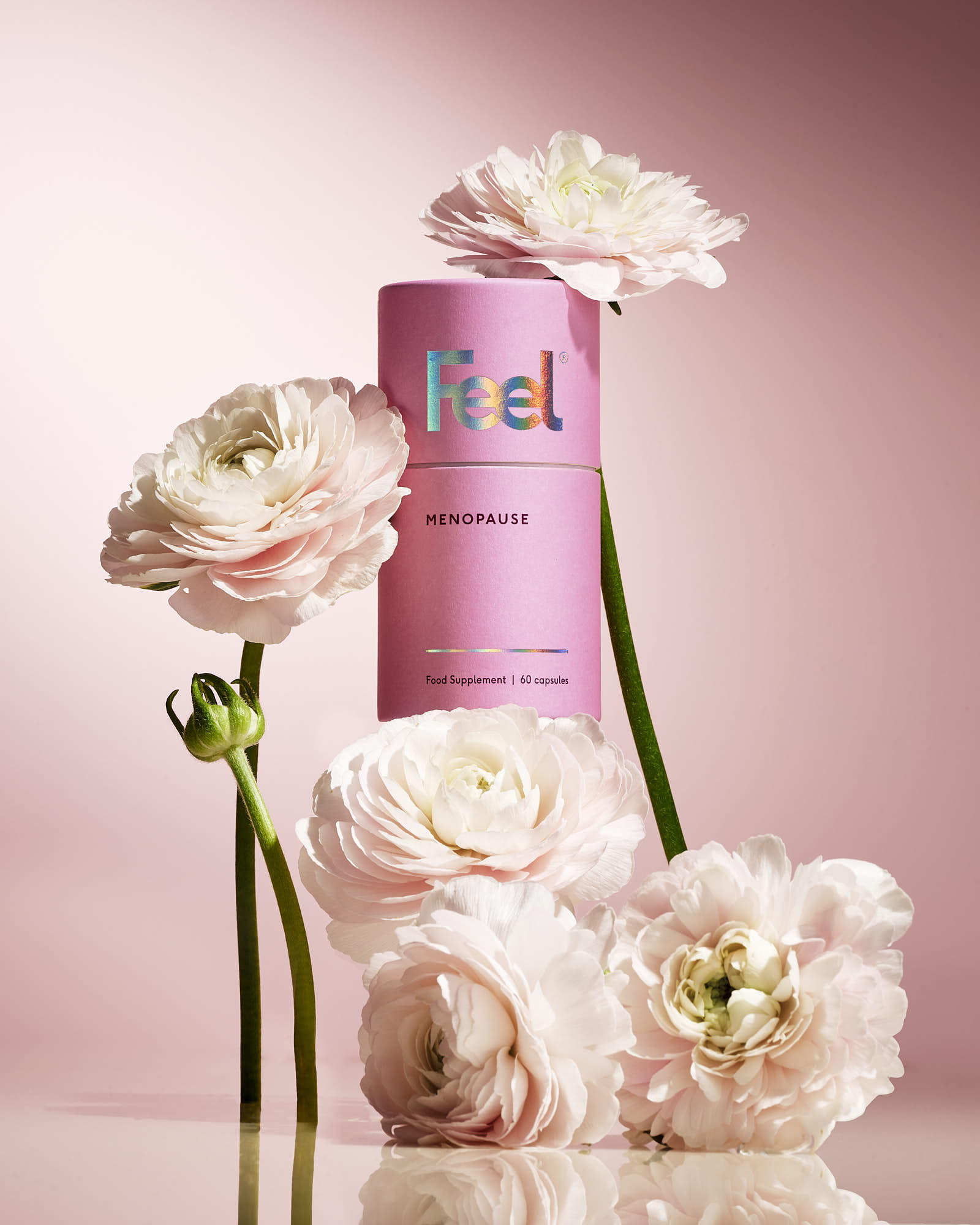 A pink cosmetic bottle surrounded by soft pink flowers on a pastel background.