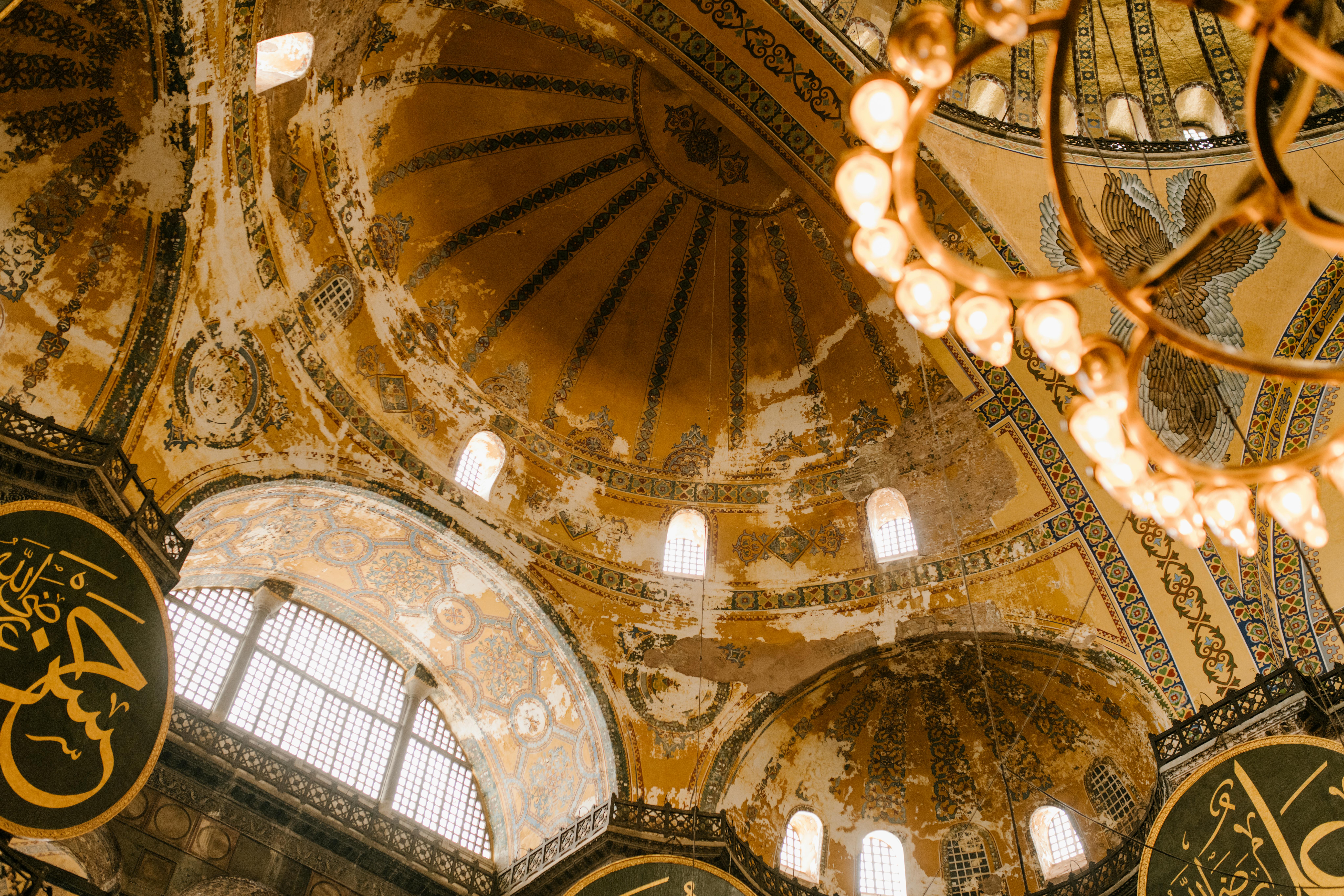 Interior dome of Hagia Sophia in Istanbul with historic golden details and chandeliers.