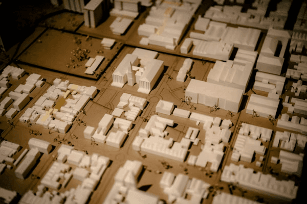 High school student conducting urban studies research with a PhD mentor, reviewing city planning maps and data