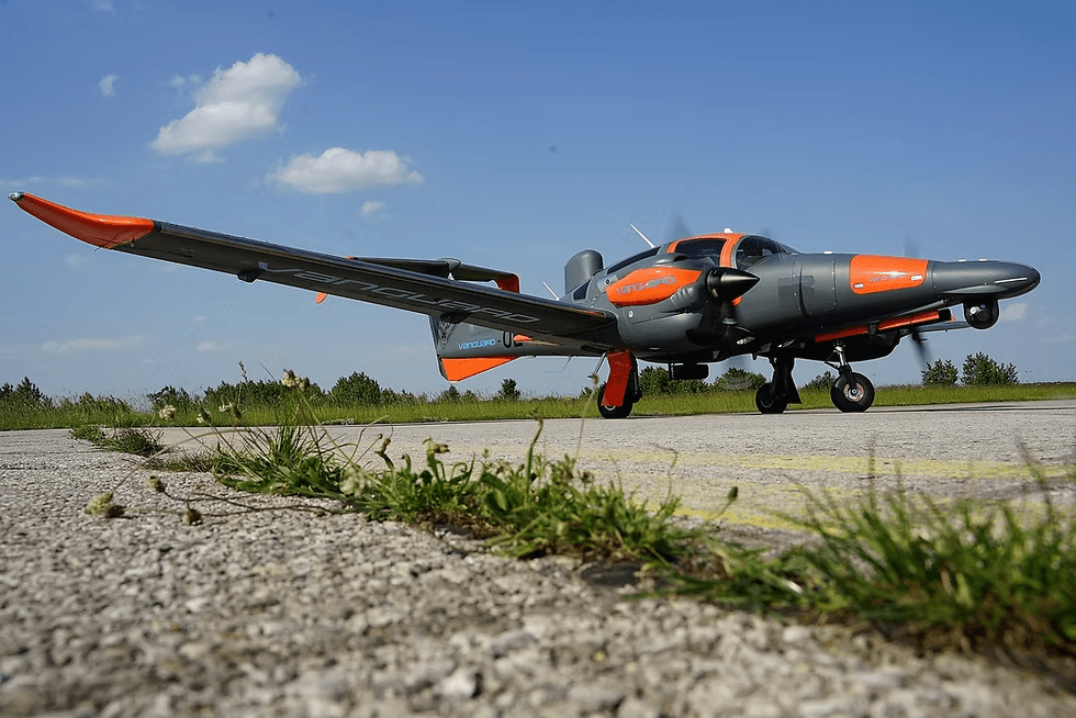 Gray and orange unmanned aircraft carrying an Overwatch Imaging payload taxiing on a runway