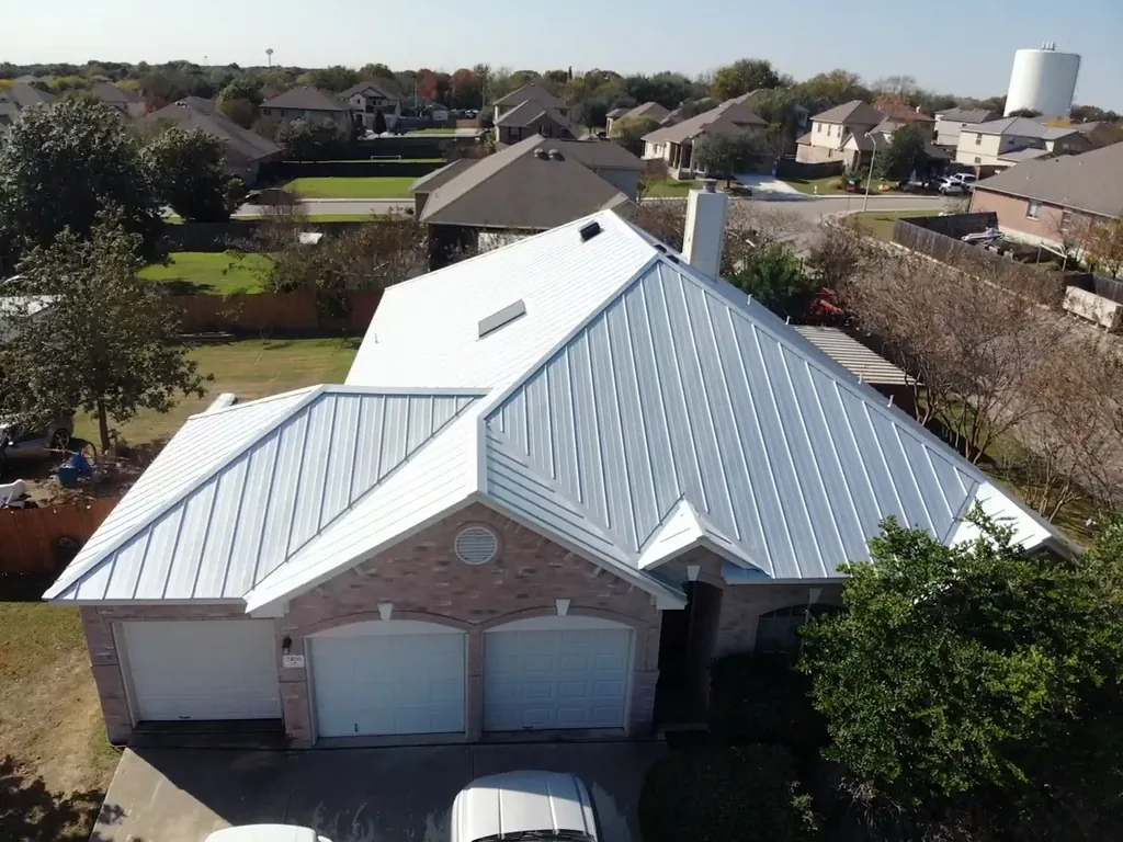 Drone view of the light-colored standing seam roof on a New Braunfels brick home, completed in 2020.