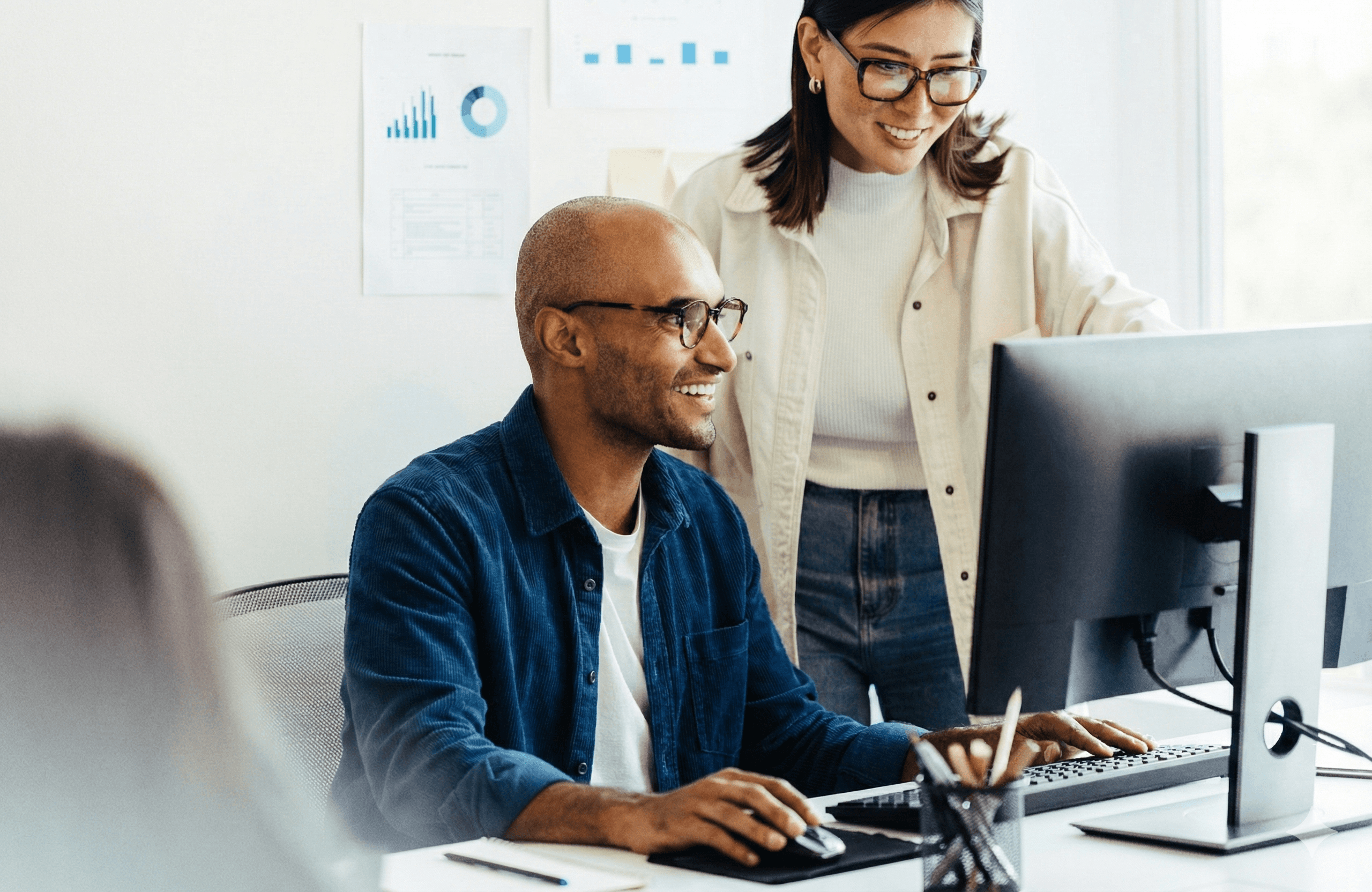 Sócios analisando gráficos de rendimento e lucro no computador, sorrindo com os resultados da economia tributária.