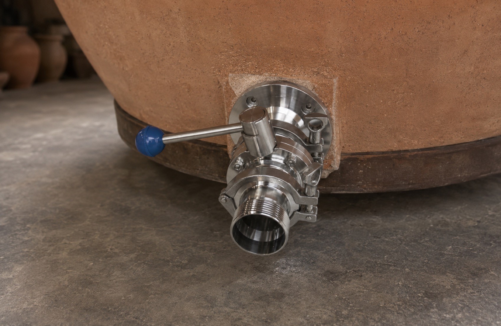 A stainless steel butterfly valve fitted to the base of a terracotta amphora