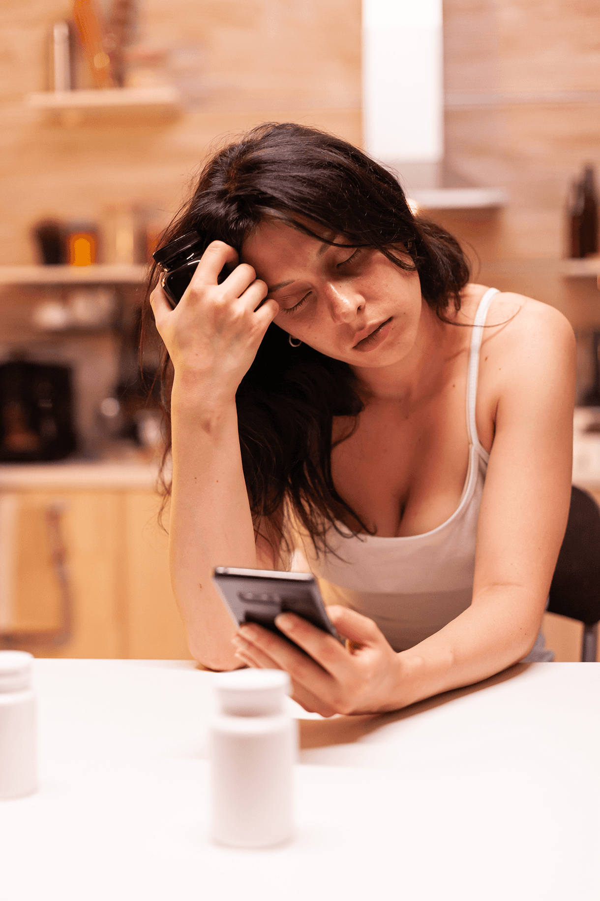 Woman holding her head in a kitchen, showing fatigue or headache as a symptom of mold exposure