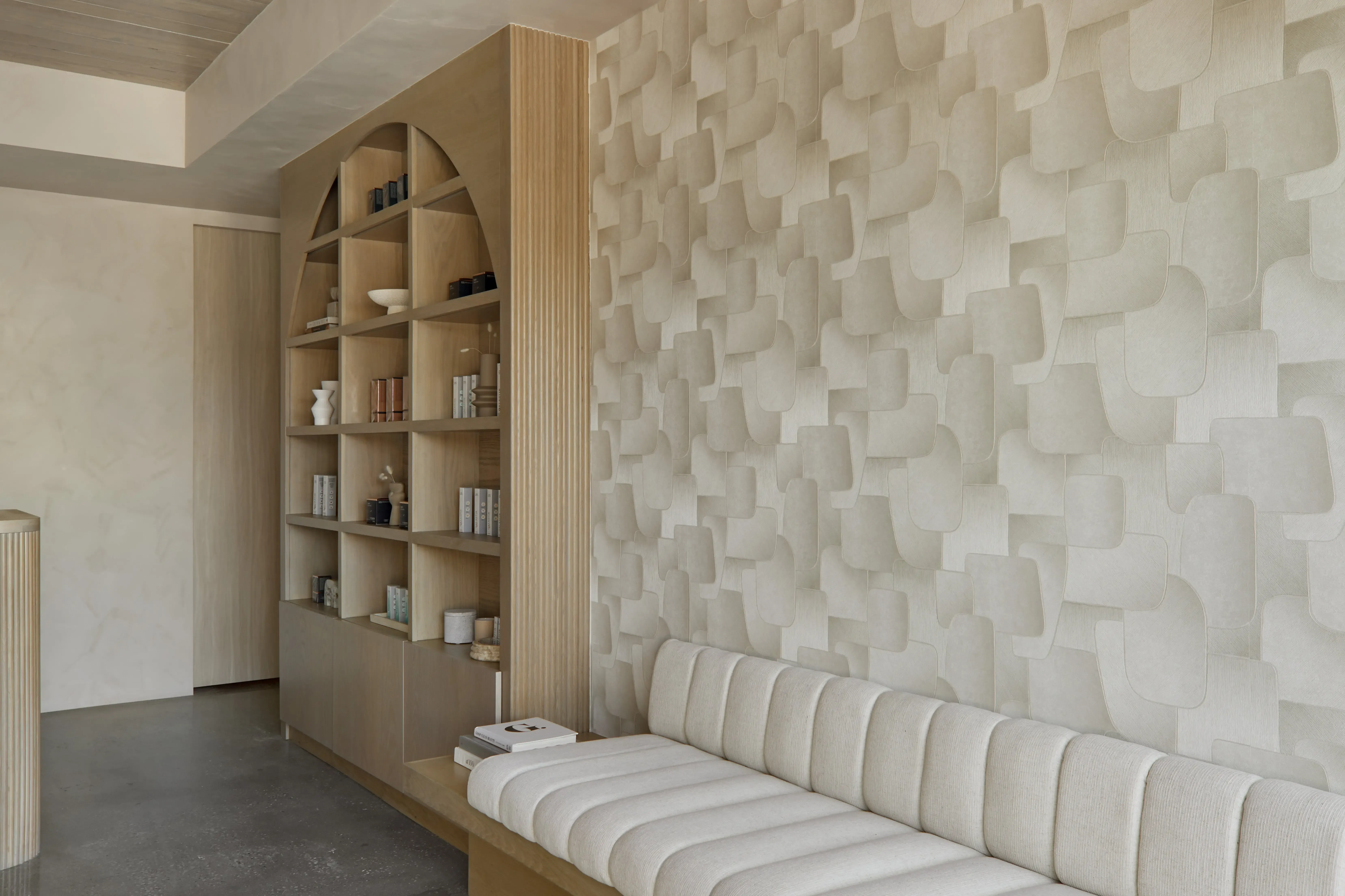 Built-in wood shelving with curated wellness products and sculptural decor in a modern studio interior.