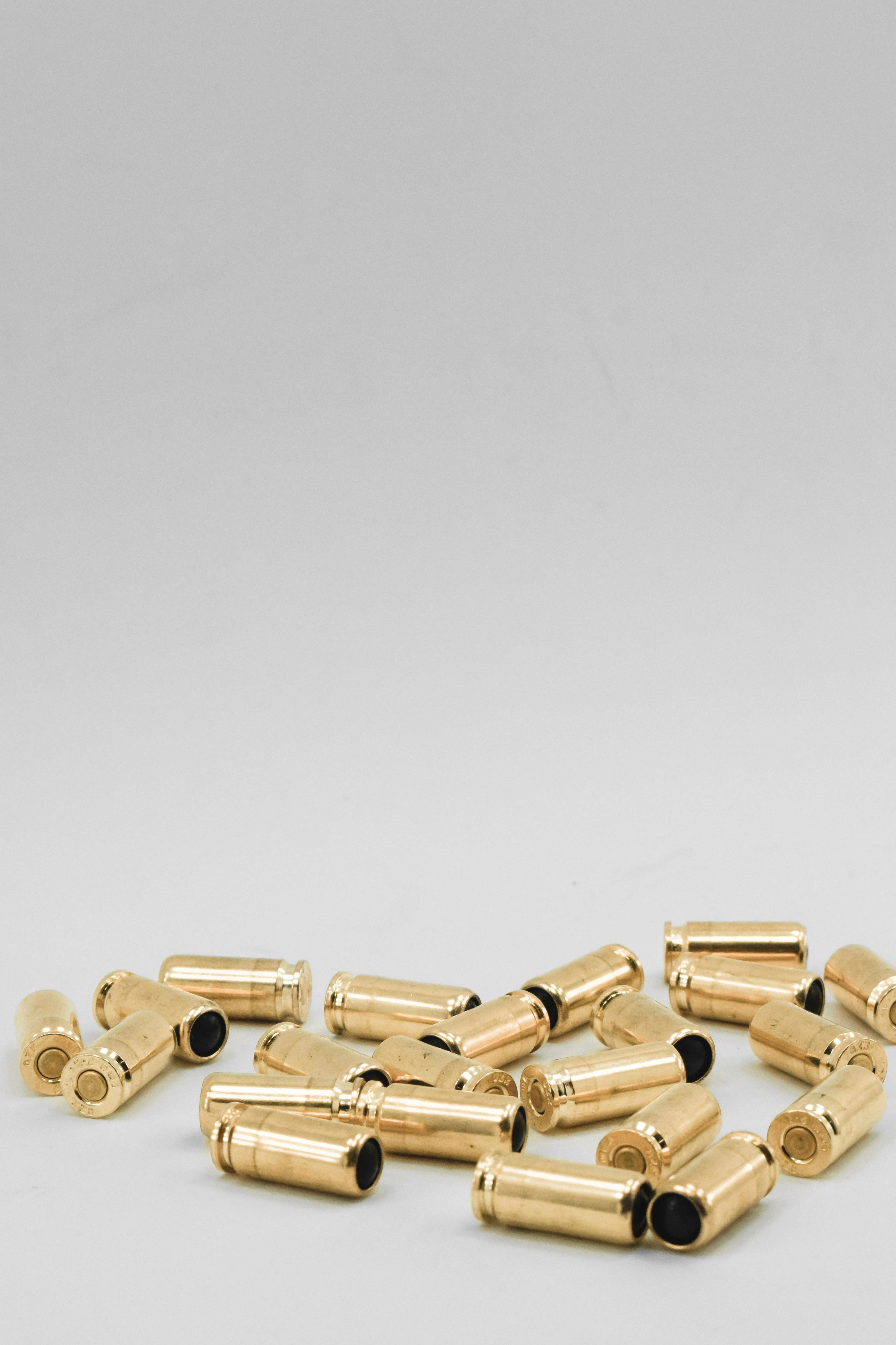 Yellow spent bullet casings scattered on a white background
