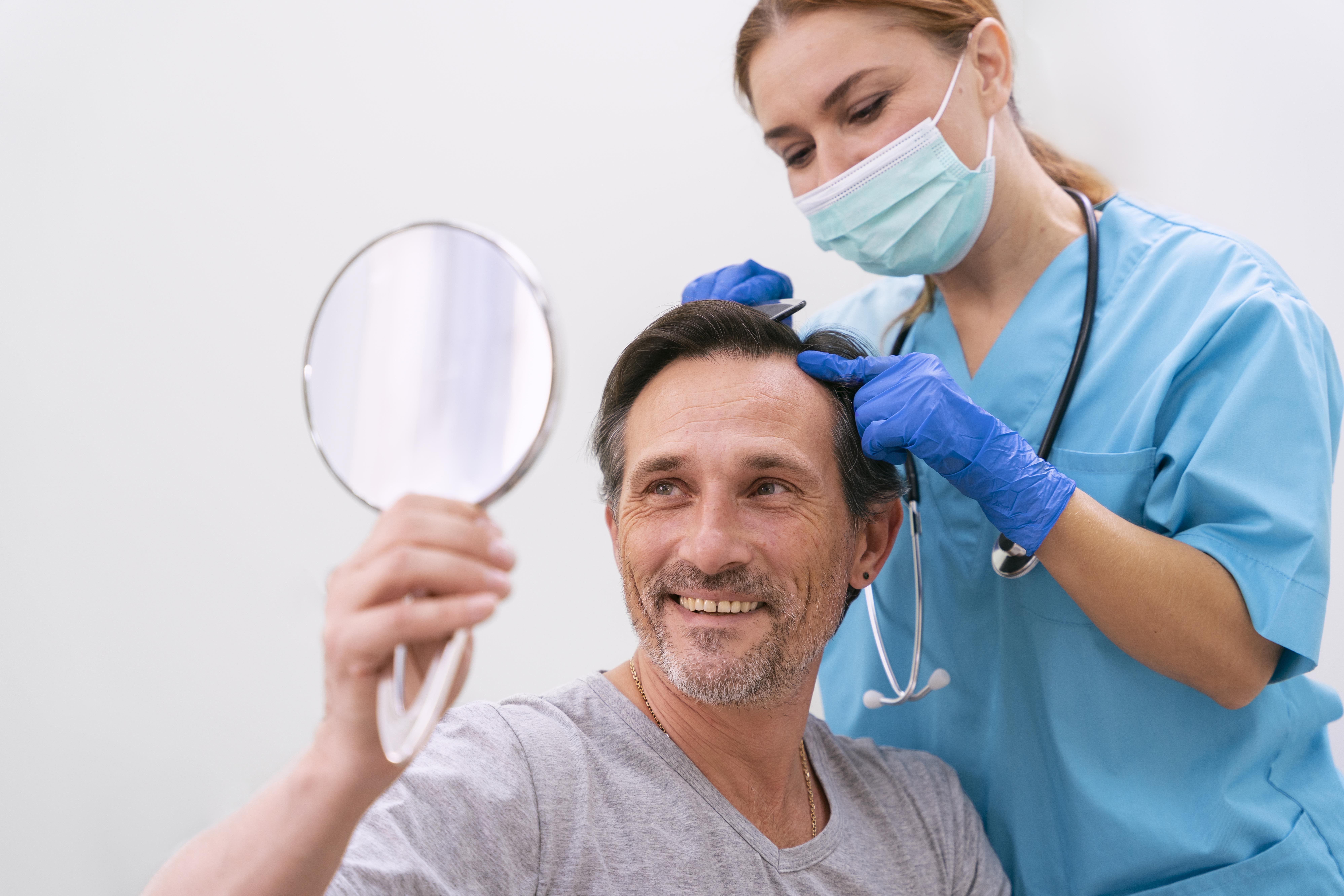 Orthodontist in dark uniform using dental mirror to examine patient’s teeth during check-up
