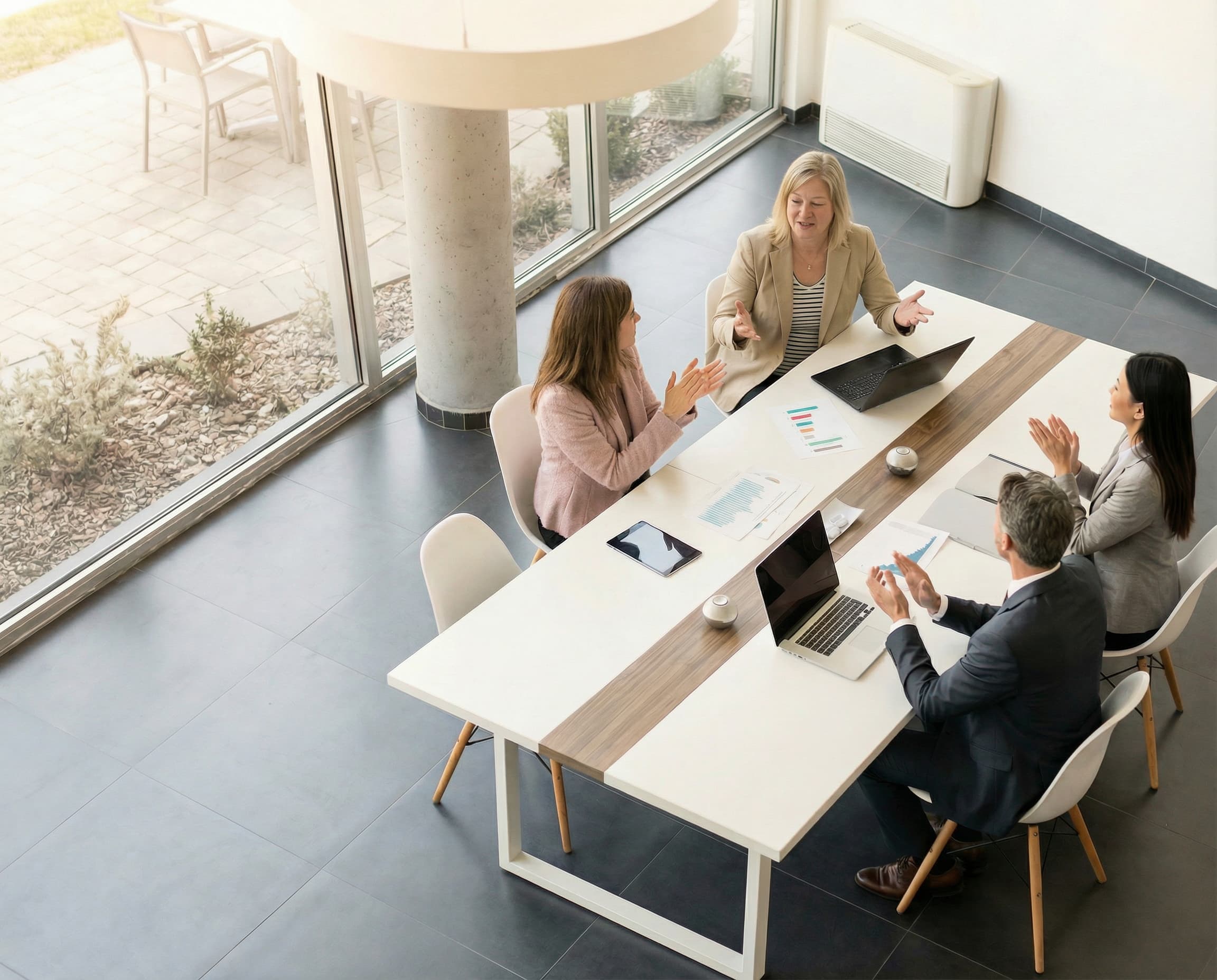 Amy and Emily and Team have meeting around a table in a modern office