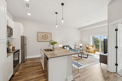A view of a kitchen and living room is presented, emphasizing a bright, inviting space with elegant design elements.